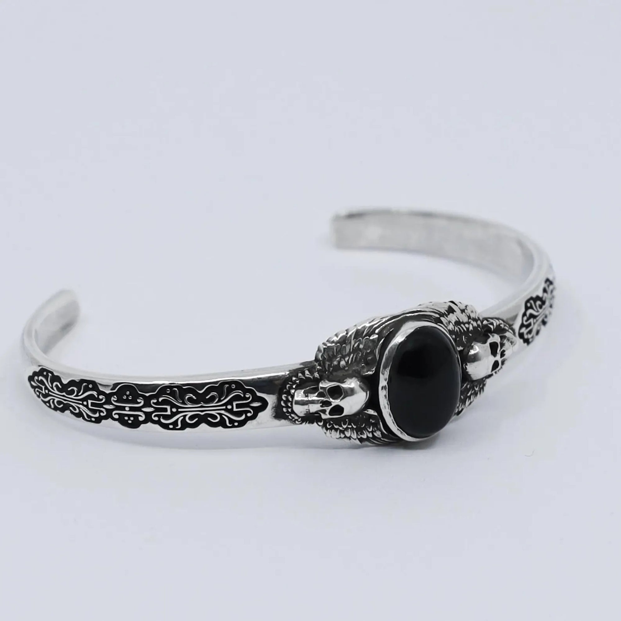 Close-up of a handcrafted black onyx skull bracelet in 925 sterling silver, reflecting gothic artistry and biker style. The polished stone and detailed engraving make it a bold accessory for men with unique taste.
