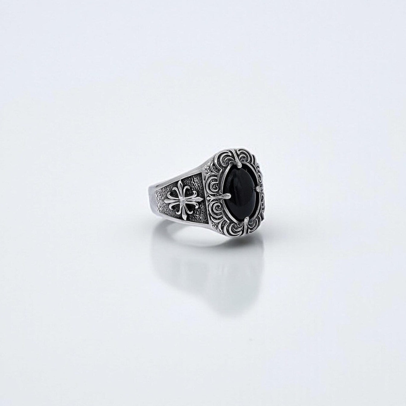 High-resolution close-up of a handcrafted gothic men's ring made from solid 925 sterling silver, featuring a polished oval-cut black onyx gemstone at the center, surrounded by detailed baroque scrollwork and dark oxidized textures—ideal for men who seek bold, symbolic jewelry that reflects strength, mystery, and timeless elegance.