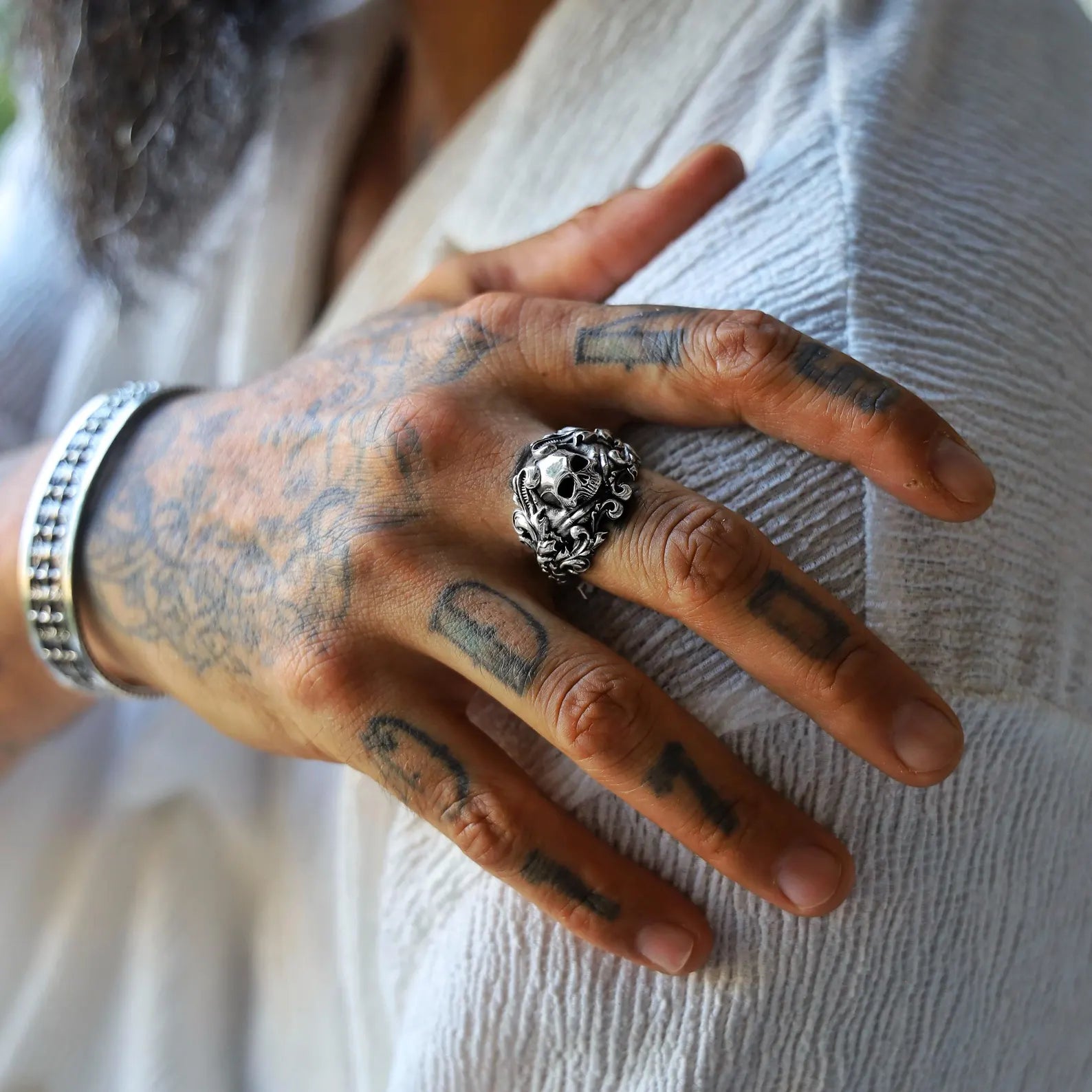 Handmade men’s skull ring in solid 925 sterling silver, showcasing a fierce skull centerpiece surrounded by swirling baroque patterns, reflecting a fusion of rebellious biker culture and vintage ornamental design.