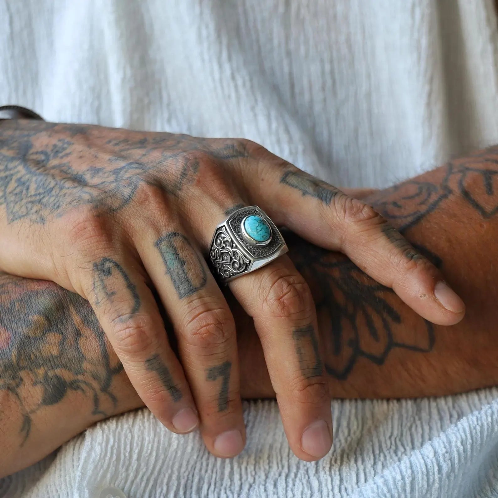 Close-up of a handcrafted men's gothic ring featuring a vibrant natural turquoise stone set in solid sterling silver, designed with bold and intricate patterns for a timeless and powerful masculine look.