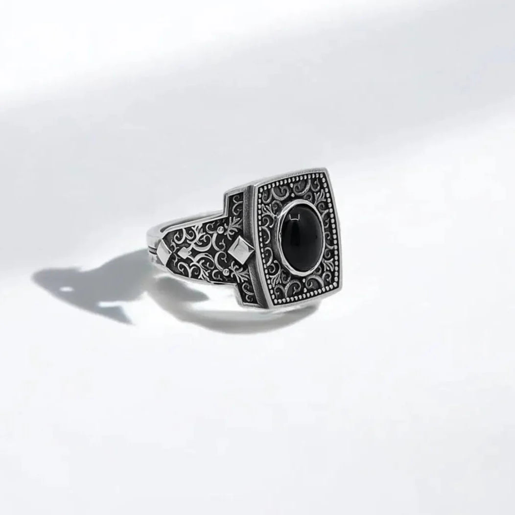 This handcrafted sterling silver onyx ring for men features a bold black gemstone set into an intricately engraved square bezel, surrounded by delicate gothic scrollwork that echoes ancient craftsmanship. Made from solid 925K silver, this mystical statement ring is a tribute to masculine energy, spiritual protection, and individual power. Ideal for those who appreciate deep symbolism in their accessories, it makes a perfect gift for a boyfriend, father, or husband with unique and elegant taste