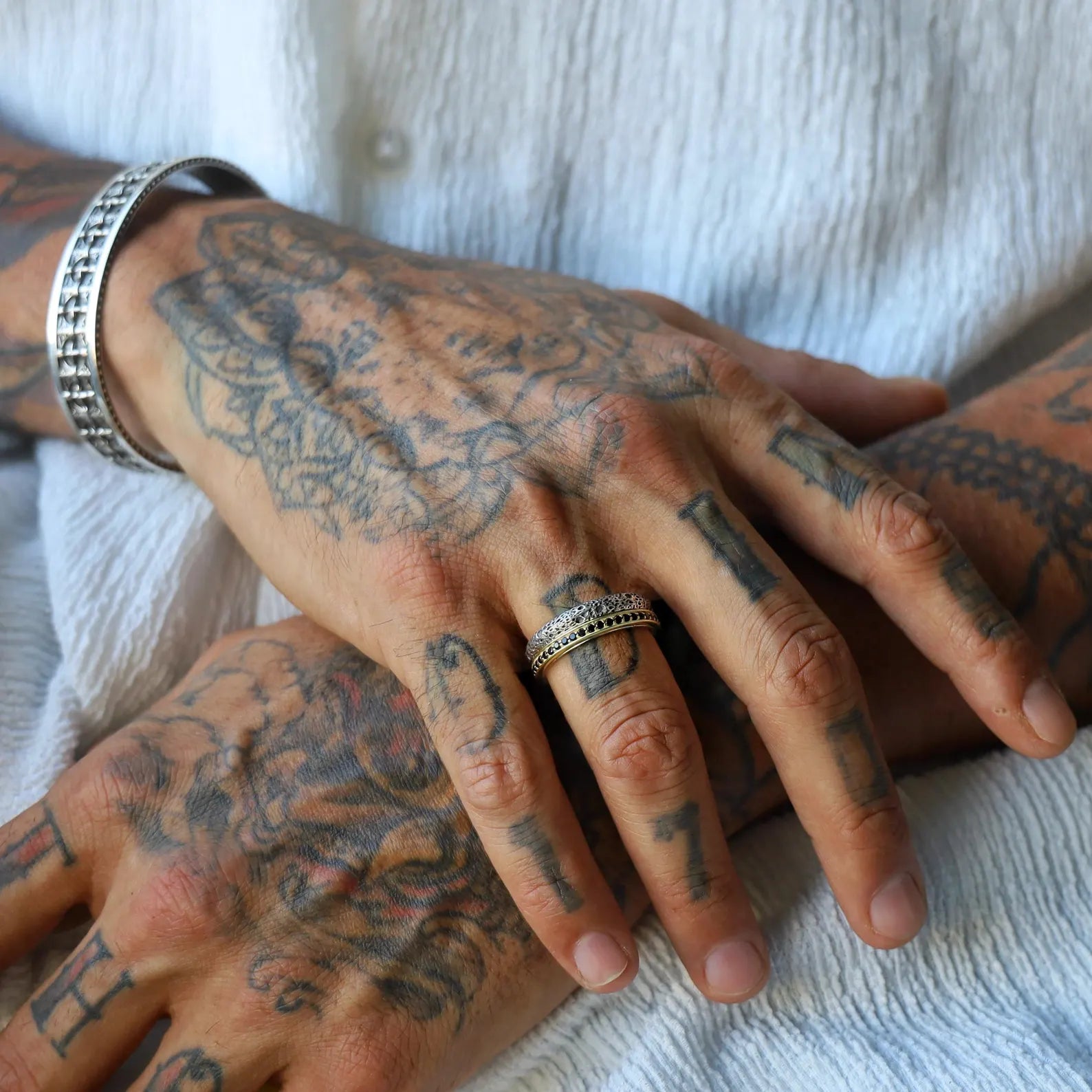 Close-up image of a handcrafted couple ring set featuring matching sterling silver wedding bands with gold-plated accents and custom engraving, designed with a unique textured finish for a timeless and personal symbol of love.