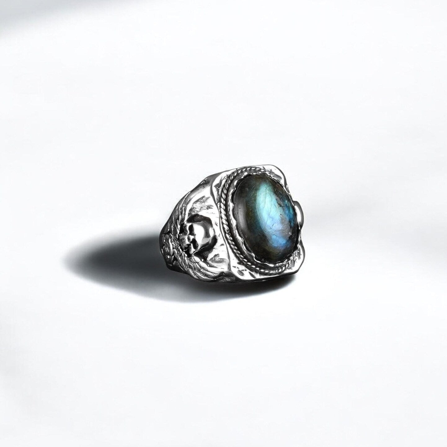 A handcrafted sterling silver ring featuring a mesmerizing natural labradorite gemstone, embraced by intricately detailed skull and wing motifs. This gothic biker ring exudes power, mystery, and individuality, making it a bold accessory for men who resonate with rock, Harley Davidson, or Western aesthetics.