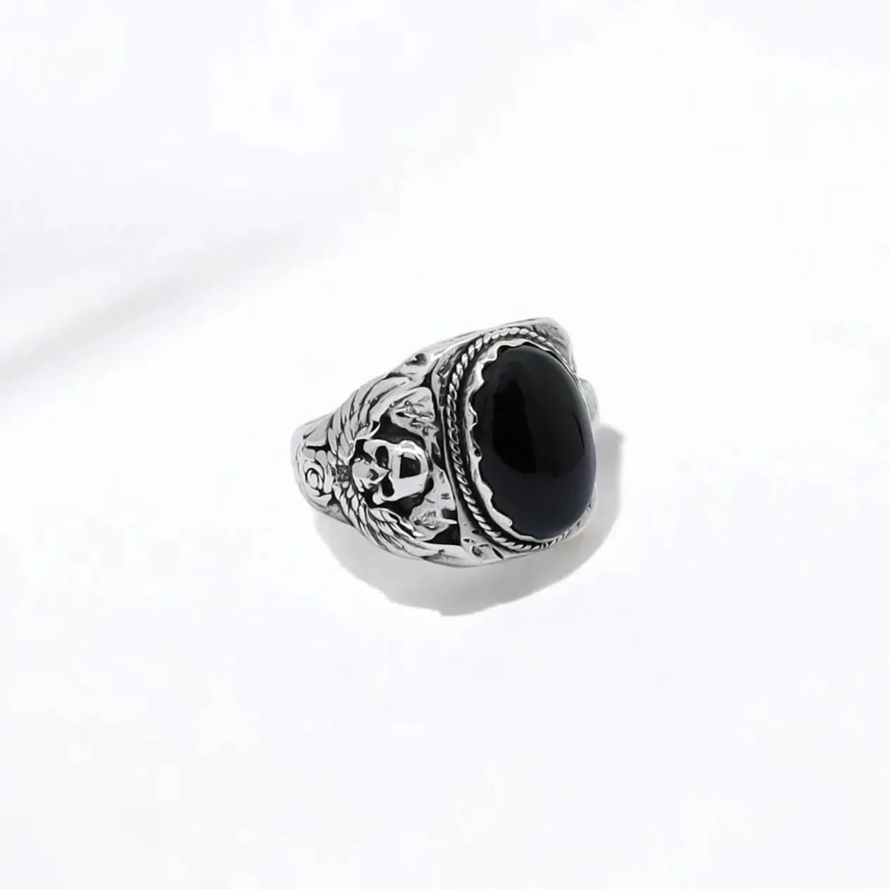 A striking silver ring featuring a black onyx gemstone encased in sculpted skulls, symbolizing protection, mortality, and power. Designed for those who seek strength in their style, this handcrafted piece is more than jewelry—it's a wearable artifact. Perfect for gothic enthusiasts, bikers, and collectors of unique, masculine silver accessories.