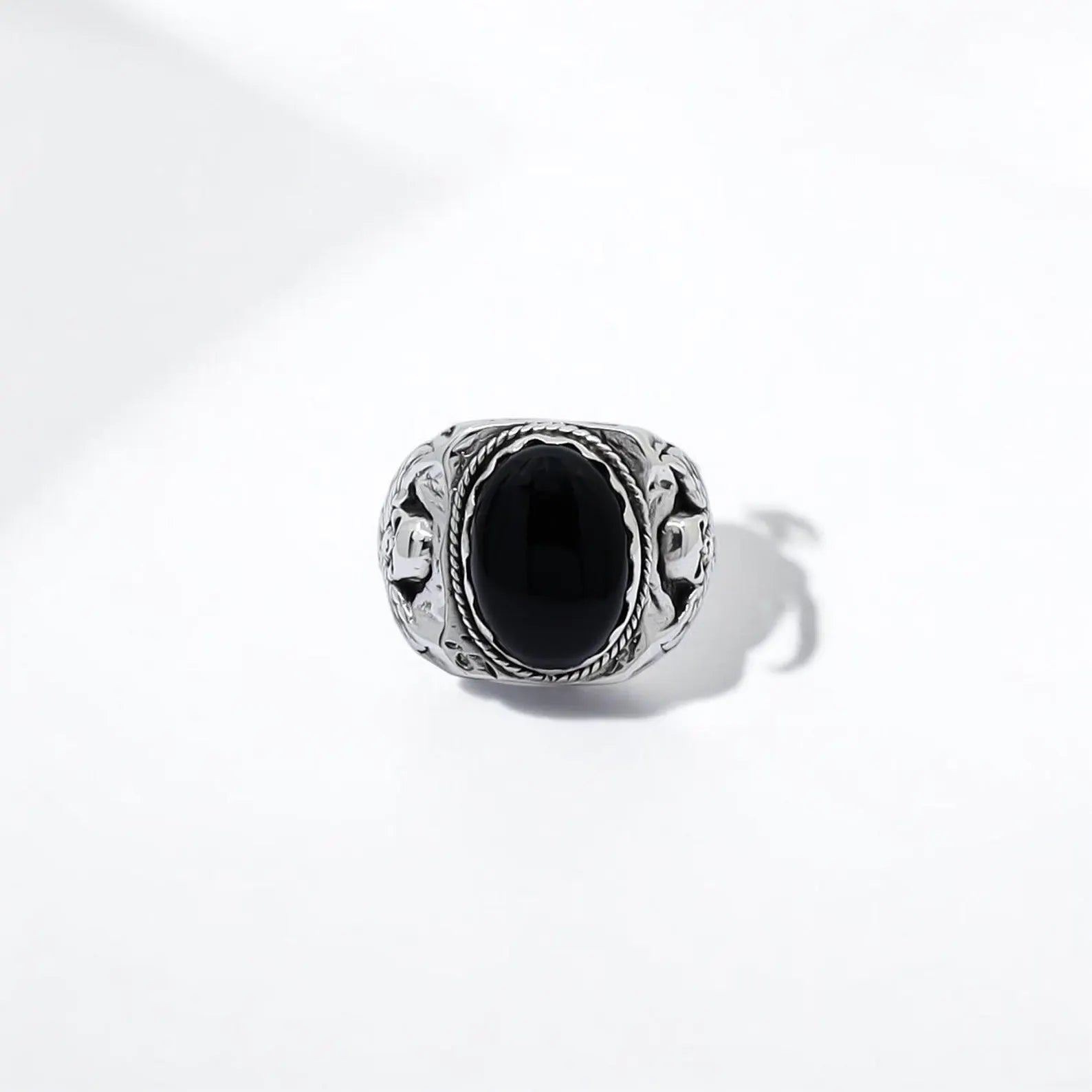 An intricately detailed silver ring featuring bold skull motifs and a polished black onyx stone, designed to represent resilience and rebellion. The handcrafted design speaks to those drawn to gothic symbolism and mysterious elegance. This unique ring for men makes an unforgettable gift for anyone who values meaningful, edgy jewelry with a story behind it.