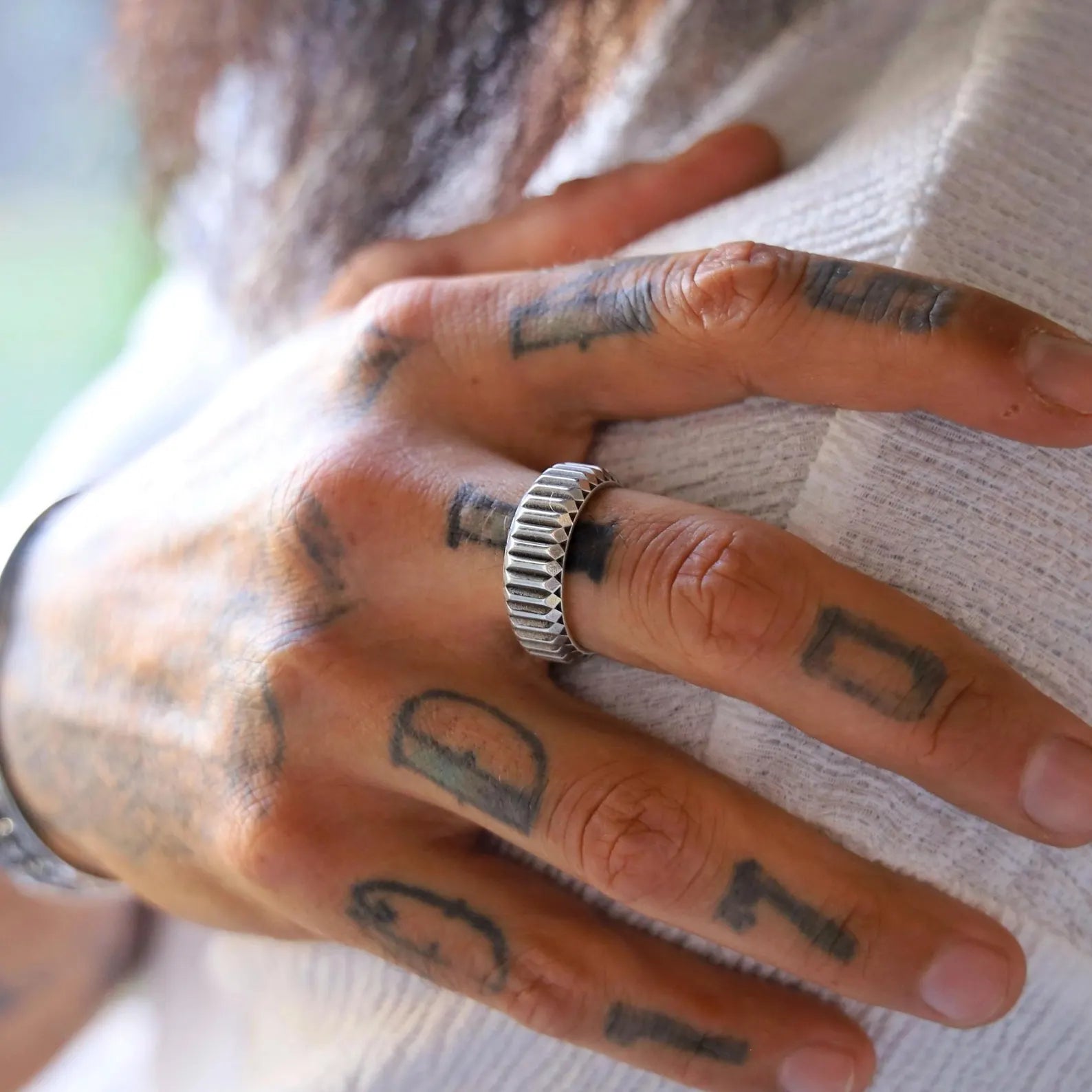Close-up image of a men’s sterling silver band ring featuring a handcrafted textured surface and clean geometric lines, offering a minimalist yet bold design perfect for everyday elegance or special occasions.