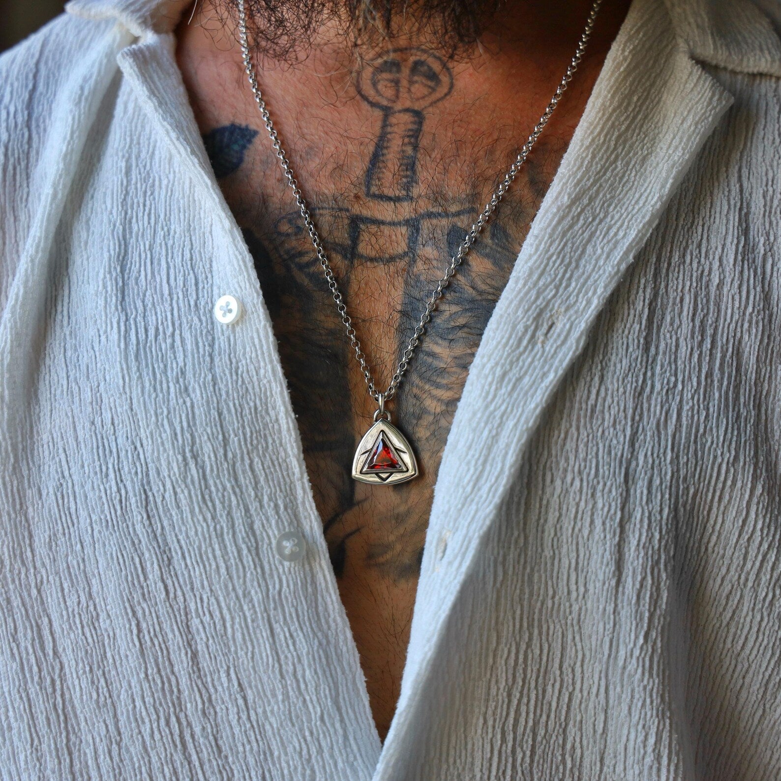 Sterling silver triangle pendant necklace with a fiery red gemstone centerpiece, designed with sharp black etching details that add contrast and depth, perfect for men and women who appreciate minimalist, bold, and symbolic jewelry styles.