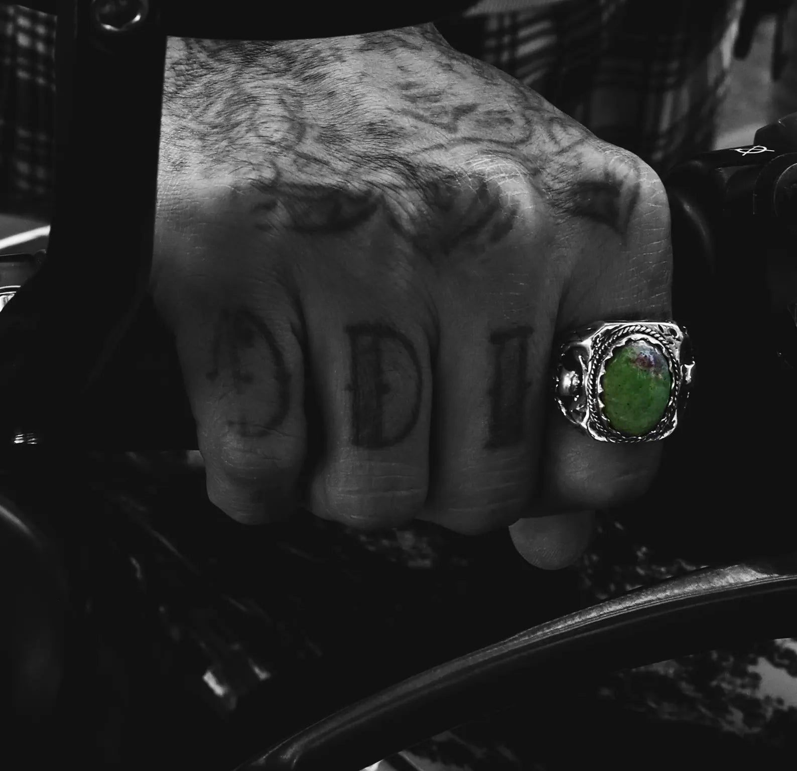 A heavy and symbolic sterling silver ring that fuses gothic aesthetics with biker culture, featuring meticulously engraved skulls and a natural gemstone full of deep green and maroon tones. Ideal for men who value handcrafted silver jewelry with attitude, meaning, and timeless style, this ring is perfect for those seeking unique gifts or bold personal pieces.
