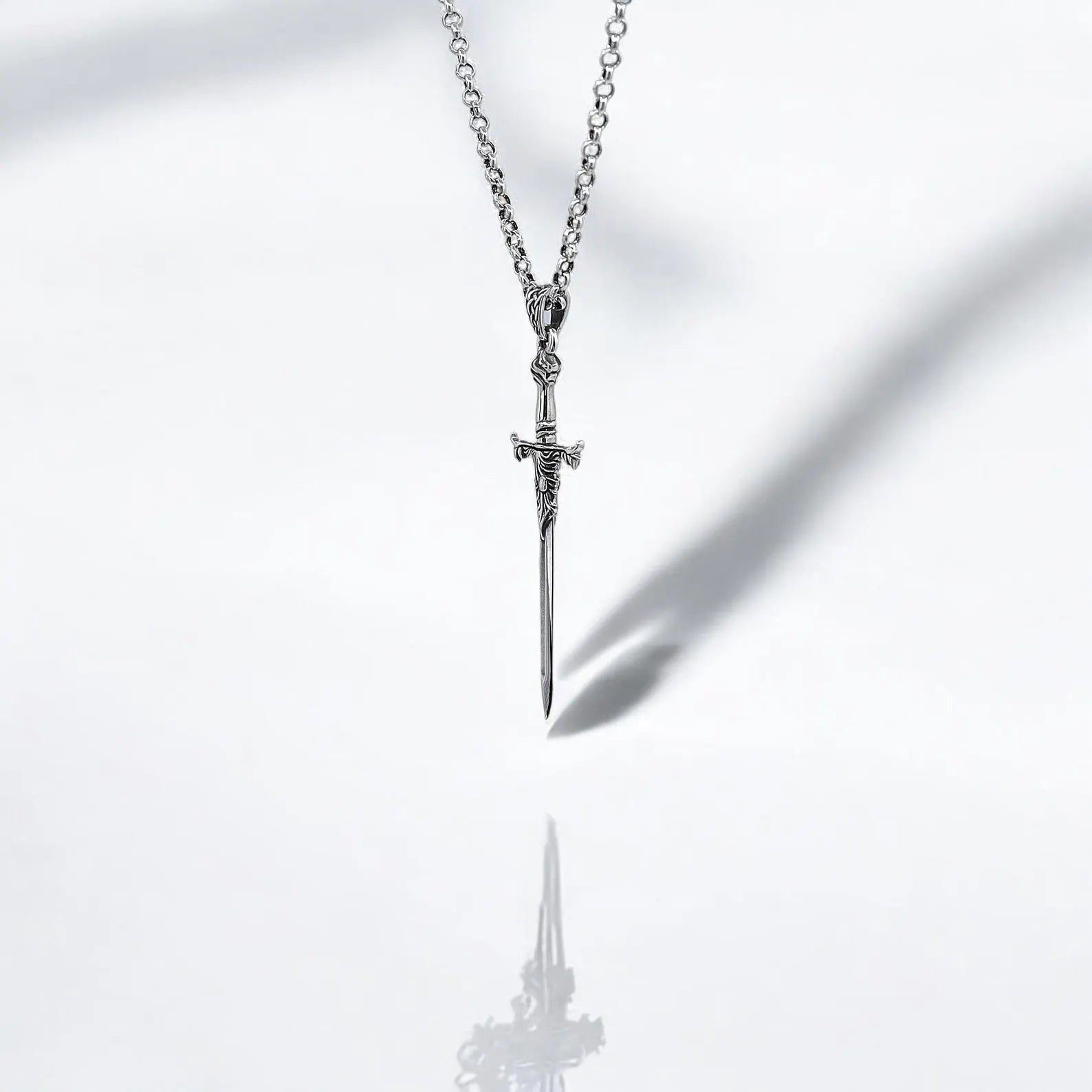 Sterling silver sword pendant handcrafted from 925K silver, showcasing detailed engravings along the hilt and blade. This warrior-inspired gothic necklace blends medieval elegance with symbolic strength, making it a powerful piece of jewelry for those who appreciate artisanal design and mythological storytelling in their fashion accessories.