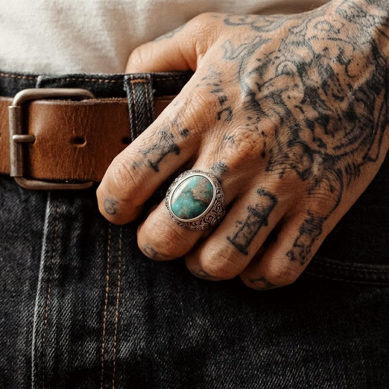 Close-up view of a men’s Baroque engraved signet ring showcasing intricate floral patterns and a natural turquoise stone set in oxidized sterling silver