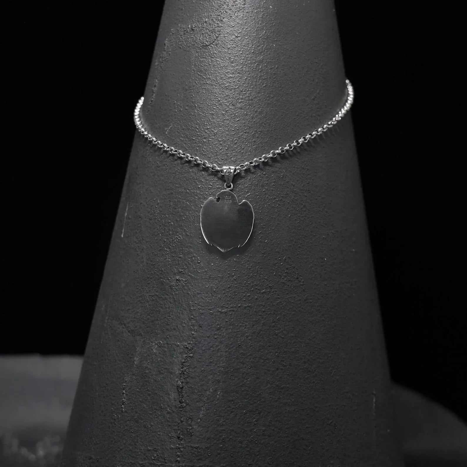 An angled close-up of the handcrafted Sterling Silver American Eagle Cross Pendant, capturing the fierce elegance of the spread-wing eagle wrapped around a detailed gothic cross. Symbolizing freedom, faith, and fearlessness, this men’s patriotic necklace is designed for those who proudly wear their beliefs. With its oxidized silver texture and precise detailing, this pendant is a powerful fusion of American heritage and gothic artistry