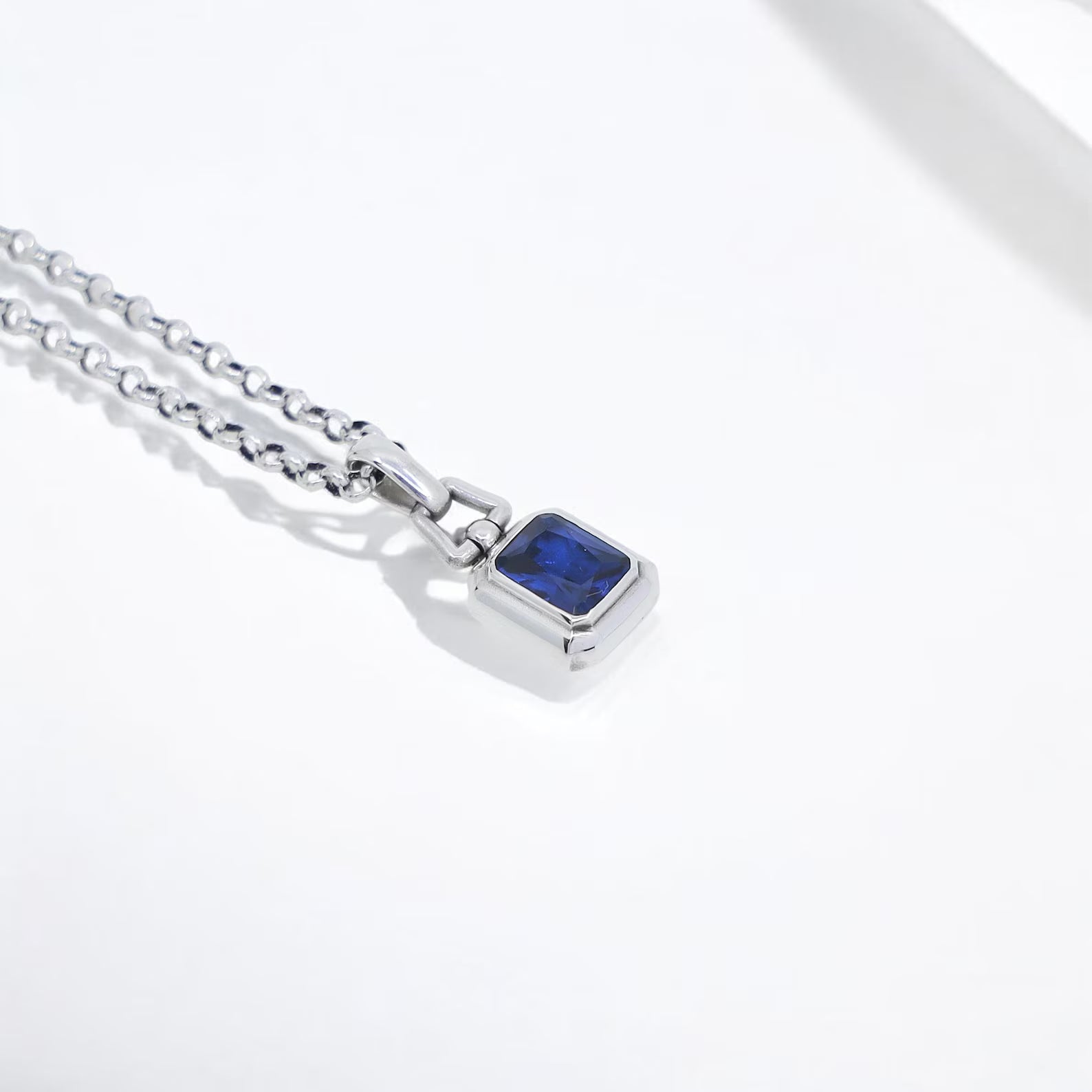 A modern sapphire pendant necklace made from high-quality sterling silver, showcasing a brilliant square-cut lab-created blue stone. This sleek men’s jewelry piece is both stylish and meaningful, ideal for layering or wearing solo.