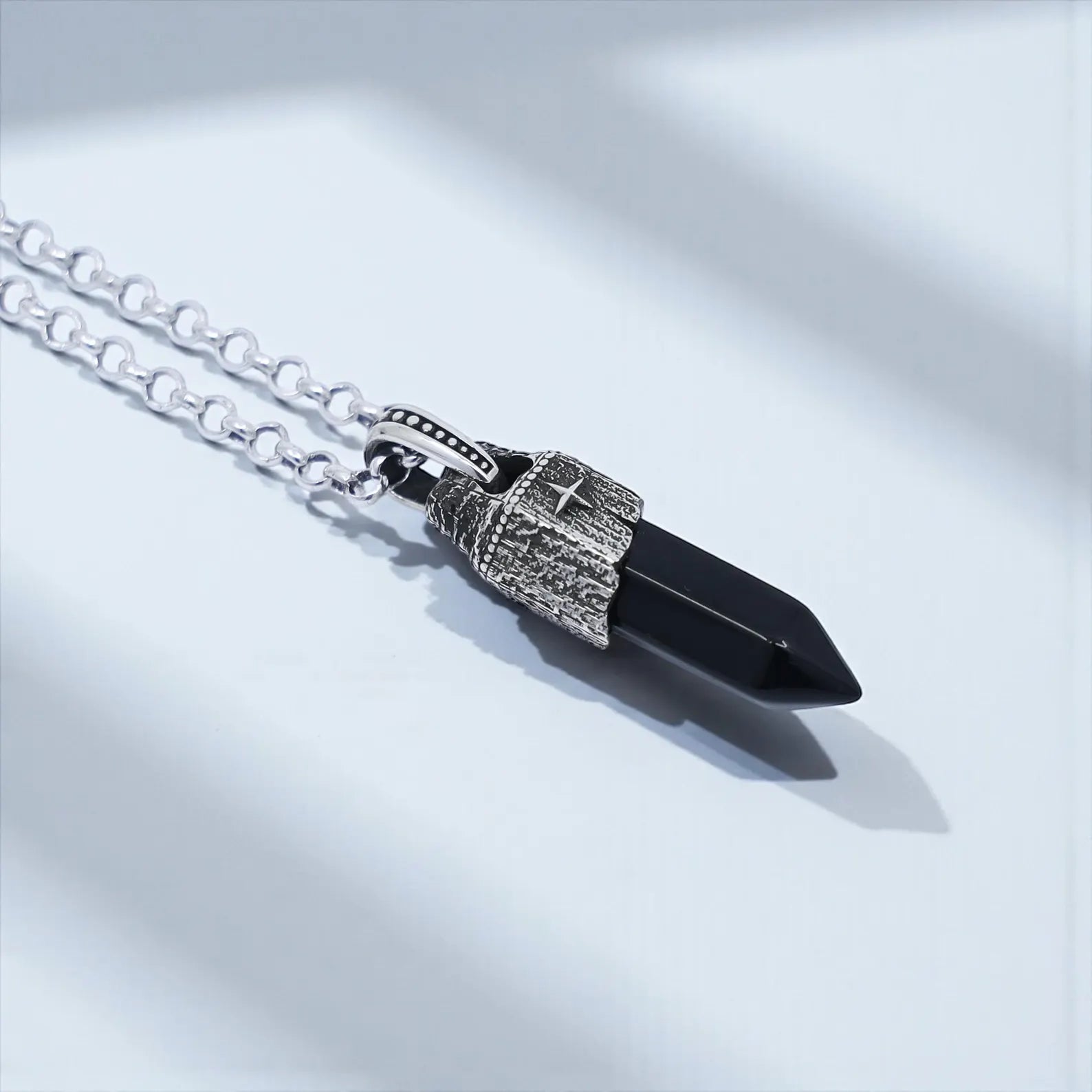 Close-up view of a vintage-inspired obsidian necklace for men, showcasing a polished black obsidian point gemstone encased in handcrafted 925 sterling silver with compass accents, minimalist spiritual jewelry with protective meaning.
