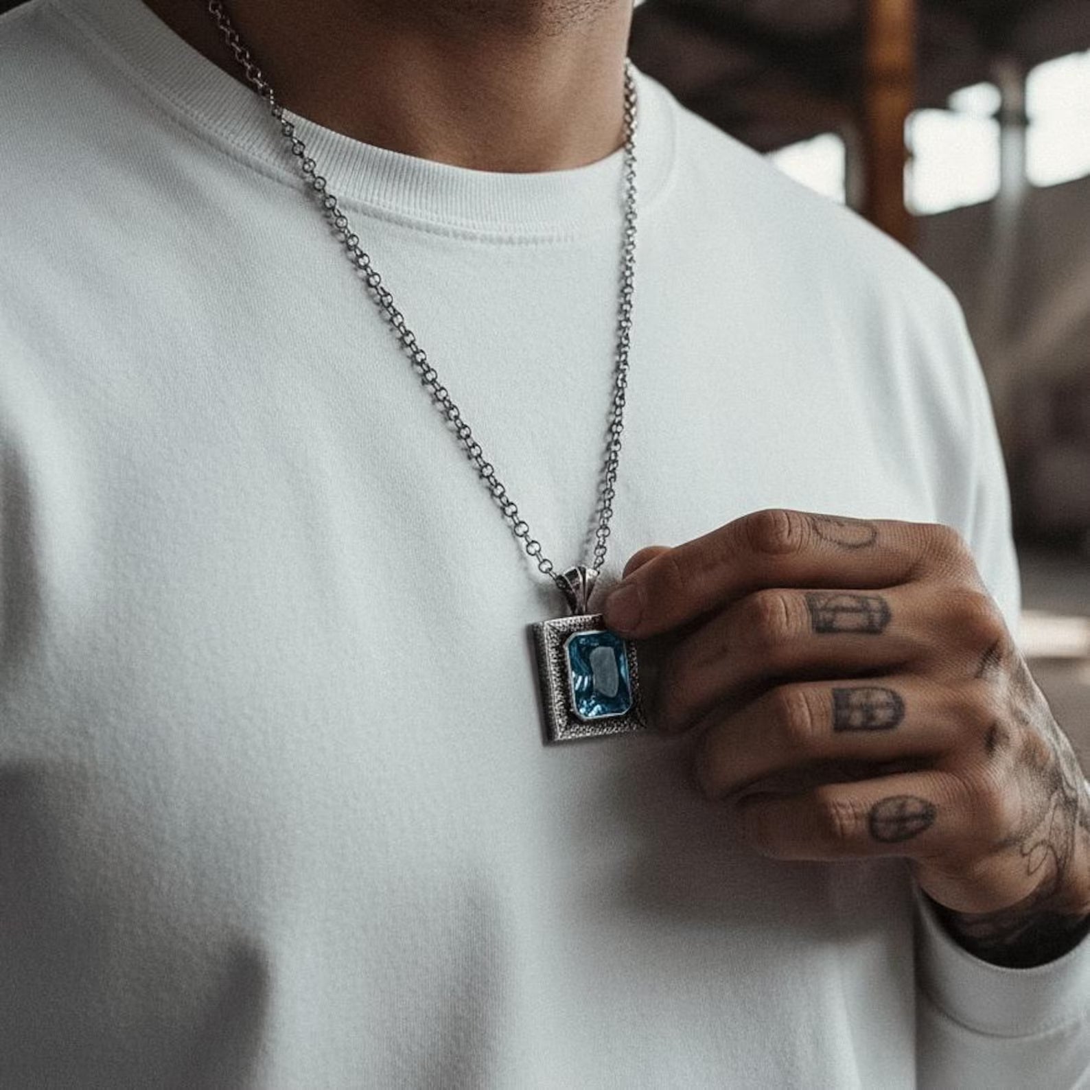 Luxury men’s blue topaz pendant necklace featuring a brilliant emerald cut stone mounted on a 925 sterling silver base with oxidized detailing. The complementary silver chain enhances the gemstone’s vivid ocean-blue hue. This handcrafted statement necklace is perfect for stylish men, gemstone lovers, and those who appreciate high-quality artisan jewelry.