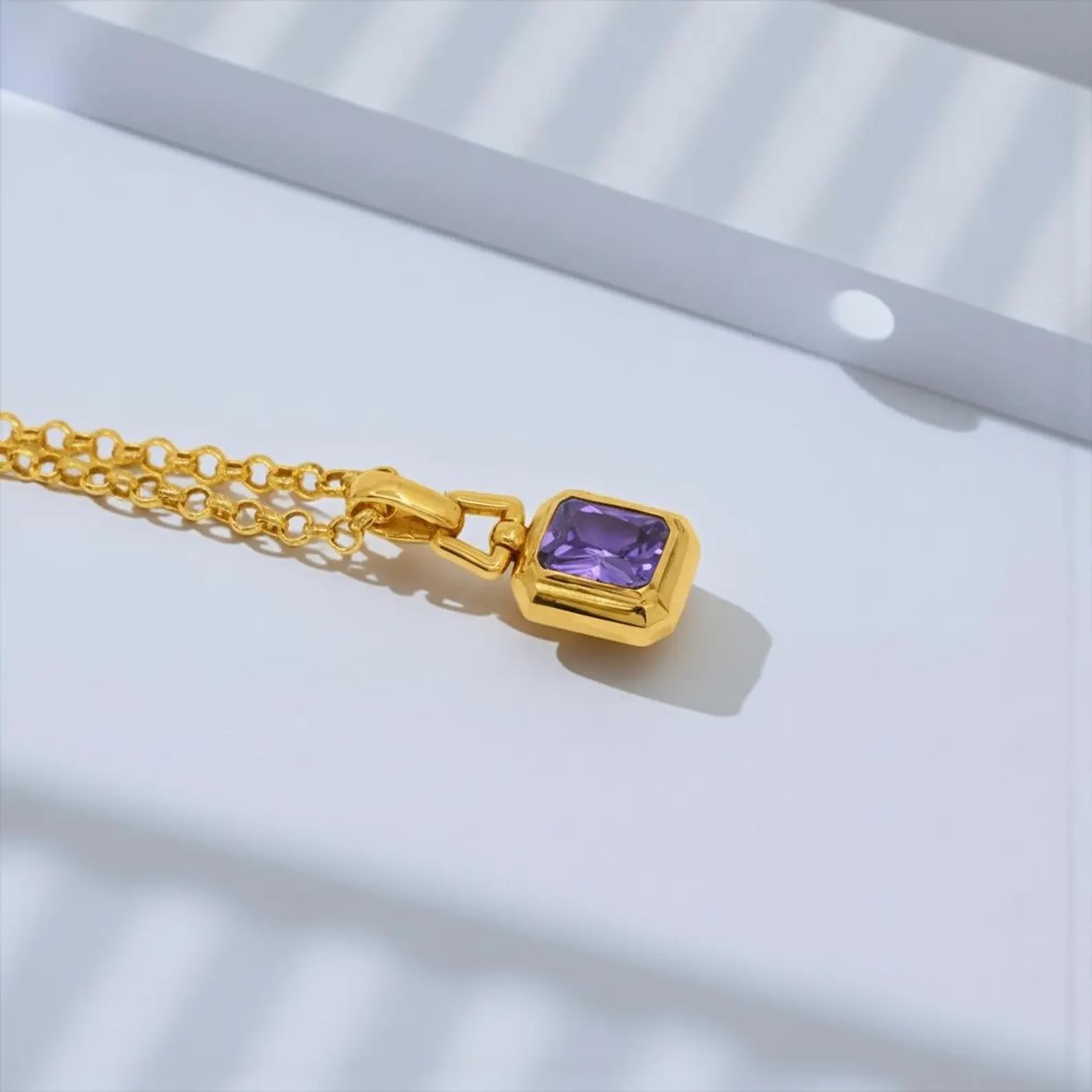 Detailed product image of a gold plated amethyst pendant necklace with sterling silver chain, emphasizing the handcrafted craftsmanship, smooth edges, and vibrant violet gemstone tone
