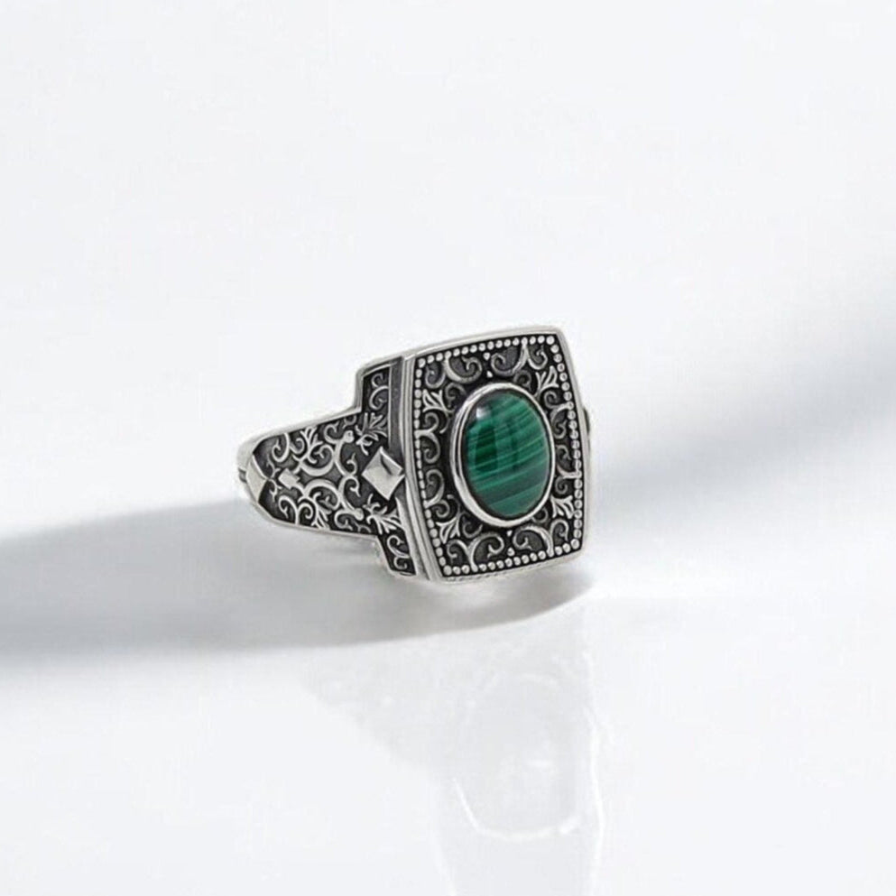 This handcrafted sterling silver malachite ring for men features a rich green oval gemstone set in a vintage-inspired square frame. Deeply engraved gothic motifs flow across the sides of the band, highlighting the ring’s old-world charm. The malachite stone, long associated with transformation and protection, makes this ring not only a bold accessory but also a meaningful symbol. Ideal for men who appreciate boho fashion with historical depth and artisan craftsmanship.