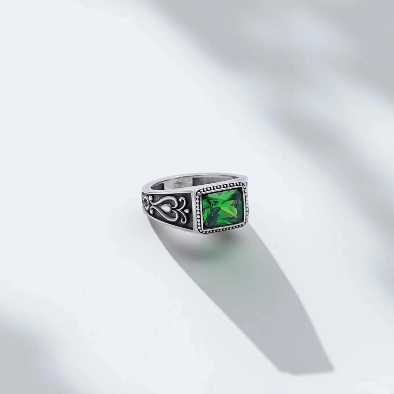 Handcrafted men’s statement ring featuring a vibrant square-cut emerald green gemstone set in oxidized sterling silver. The band showcases gothic ornamental engravings, combining timeless elegance with bold masculine energy — perfect for gothic jewelry lovers or unique gift seekers.