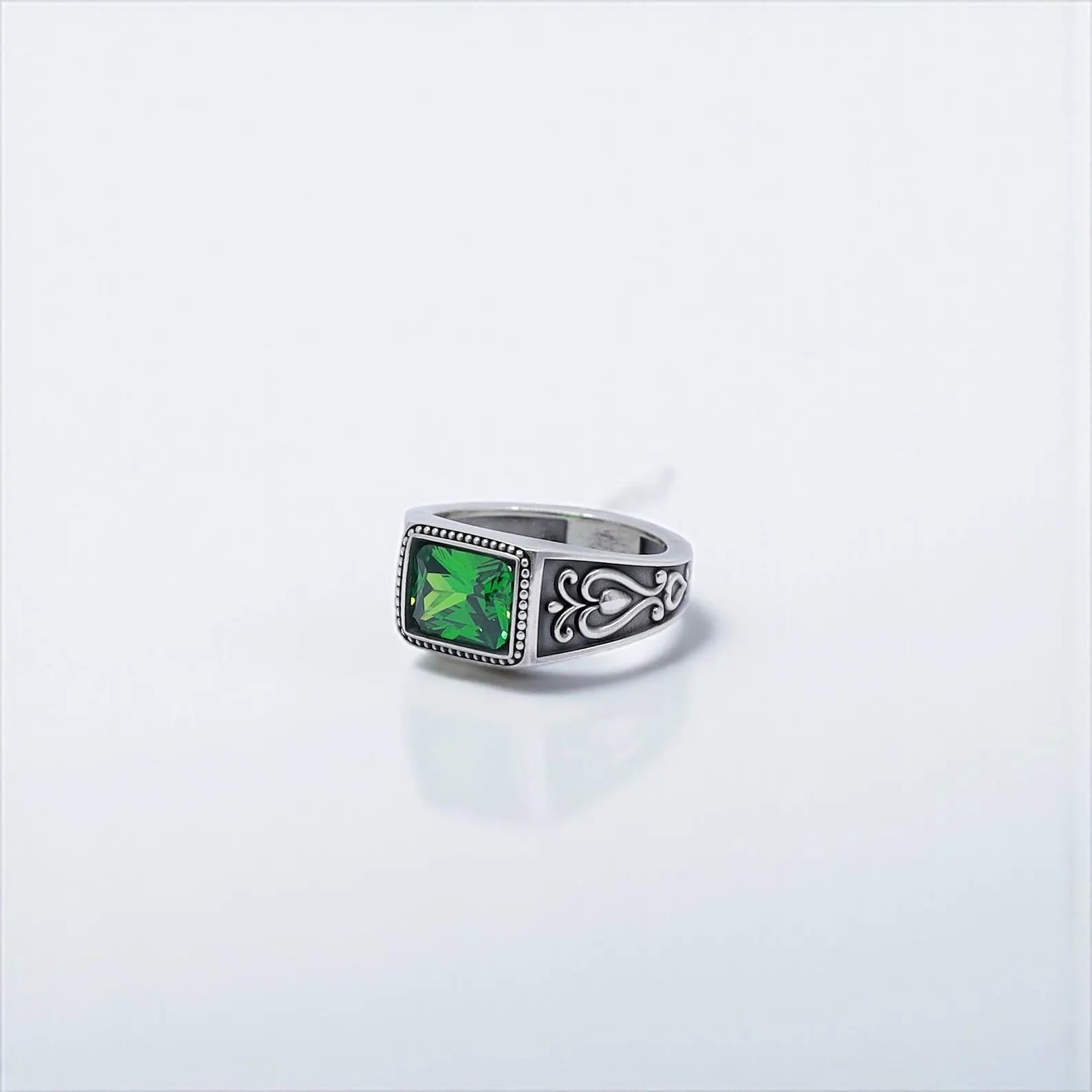 Artisan-made statement ring for men, showcasing a square emerald stone set in a thick sterling silver band with intricate gothic detailing. Its handcrafted finish and symbolic dark green gemstone make it a standout piece for gothic fashion, biker style, or alternative accessories.