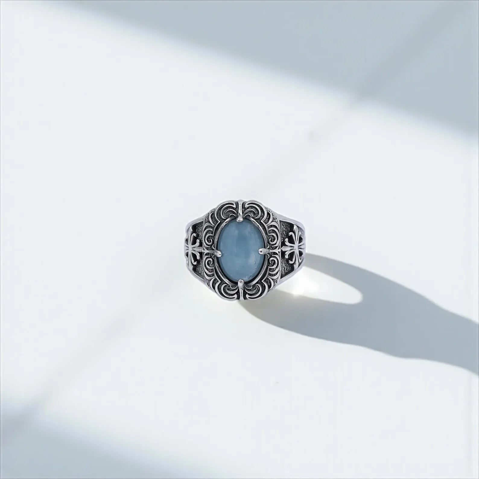 A unique aquamarine silver ring with gothic flair, designed for men who seek statement jewelry. The polished blue gemstone is securely set in ornate prongs surrounded by medieval patterns. Great for Shopify gothic jewelry shops, Pinterest gift guides, or Instagram reels showcasing bold men’s style.
