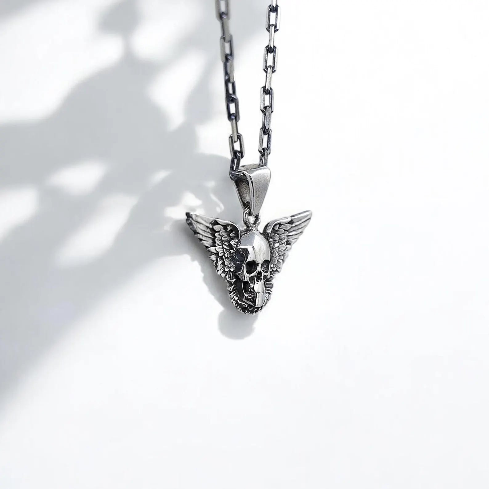 This handcrafted sterling silver gothic skull necklace features a mesmerizing skull motif with wide, detailed wings that stretch across the pendant, symbolizing both rebellion and spiritual freedom. Perfect for fans of rocker fashion, alternative style, and occult symbolism, this necklace makes a dramatic fashion statement while also serving as a protective talisman. The oxidized finish highlights every carved detail