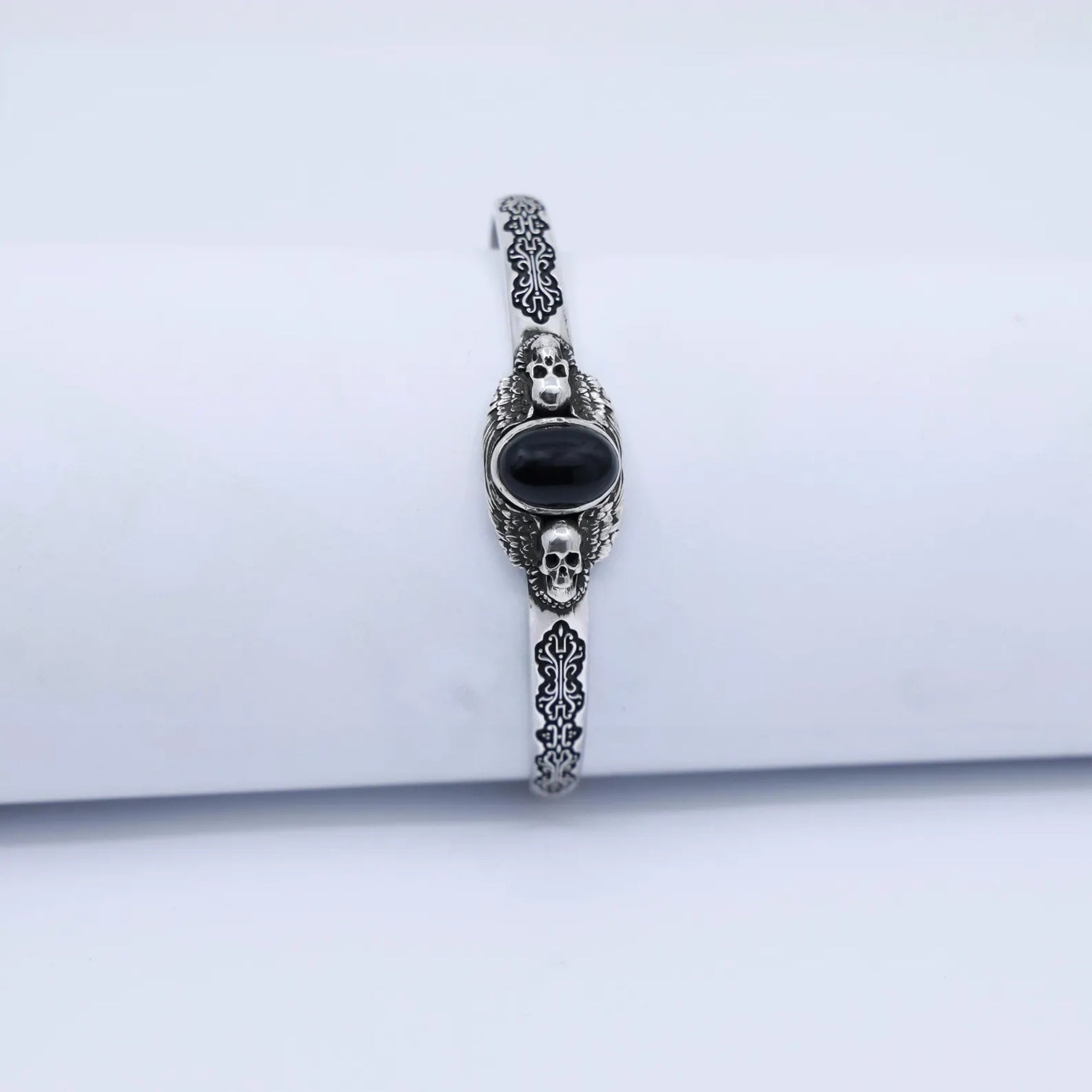 Handcrafted 925 sterling silver skull bracelet with a smooth black onyx gemstone centerpiece. The detailed engravings and polished oxidized finish highlight fine craftsmanship, making it a stunning gothic men’s accessory.