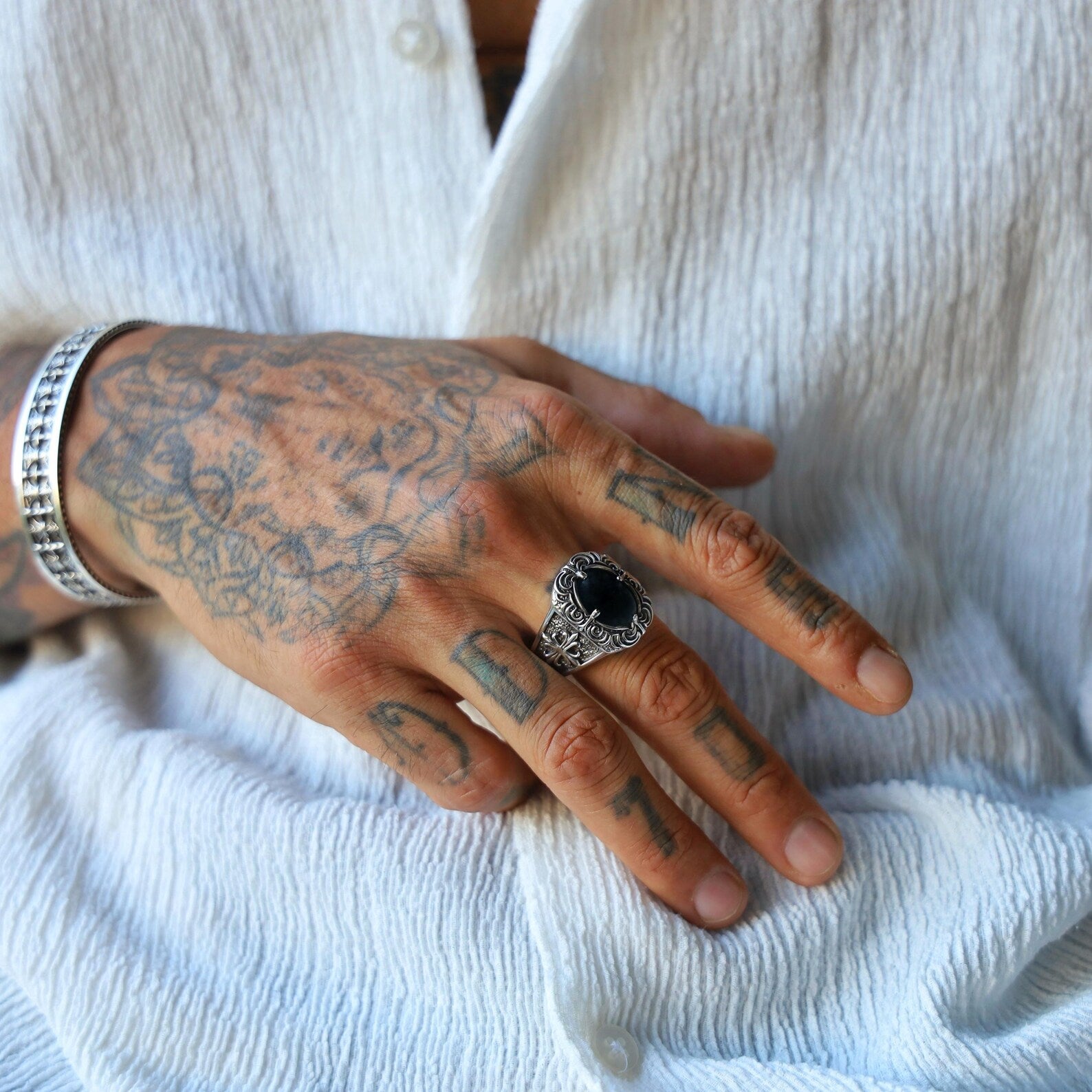 Sterling silver men's ring with a polished black onyx centerpiece, designed in a gothic biker style with intricate metalwork and a rugged finish, perfect as a bold gift for him.