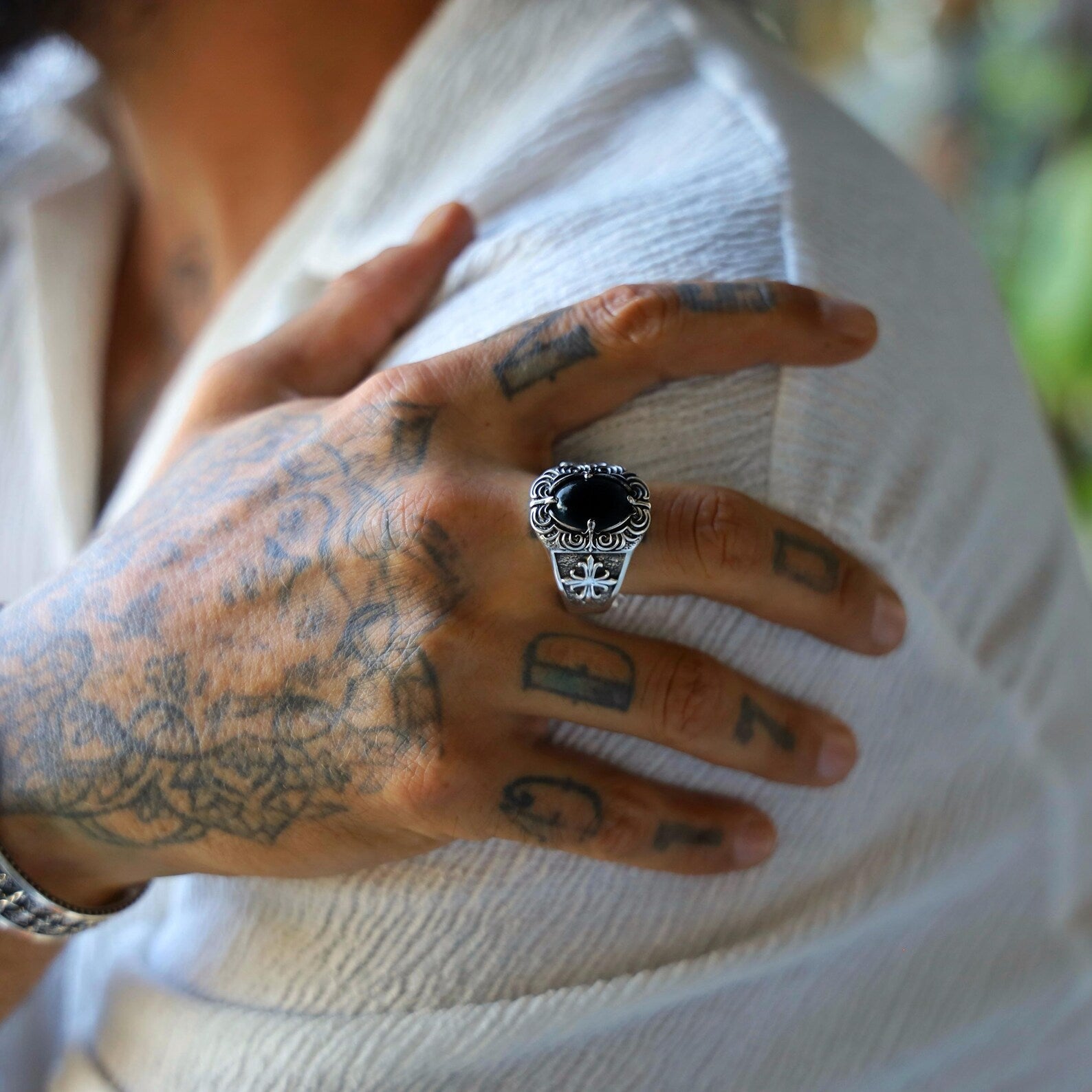 Detailed product image of a gothic-style biker ring for men, highlighting the luxurious shine of the black onyx gemstone set in an intricately carved 925 silver band, designed for those who appreciate artisan jewelry with medieval, spiritual, or masculine symbolism.