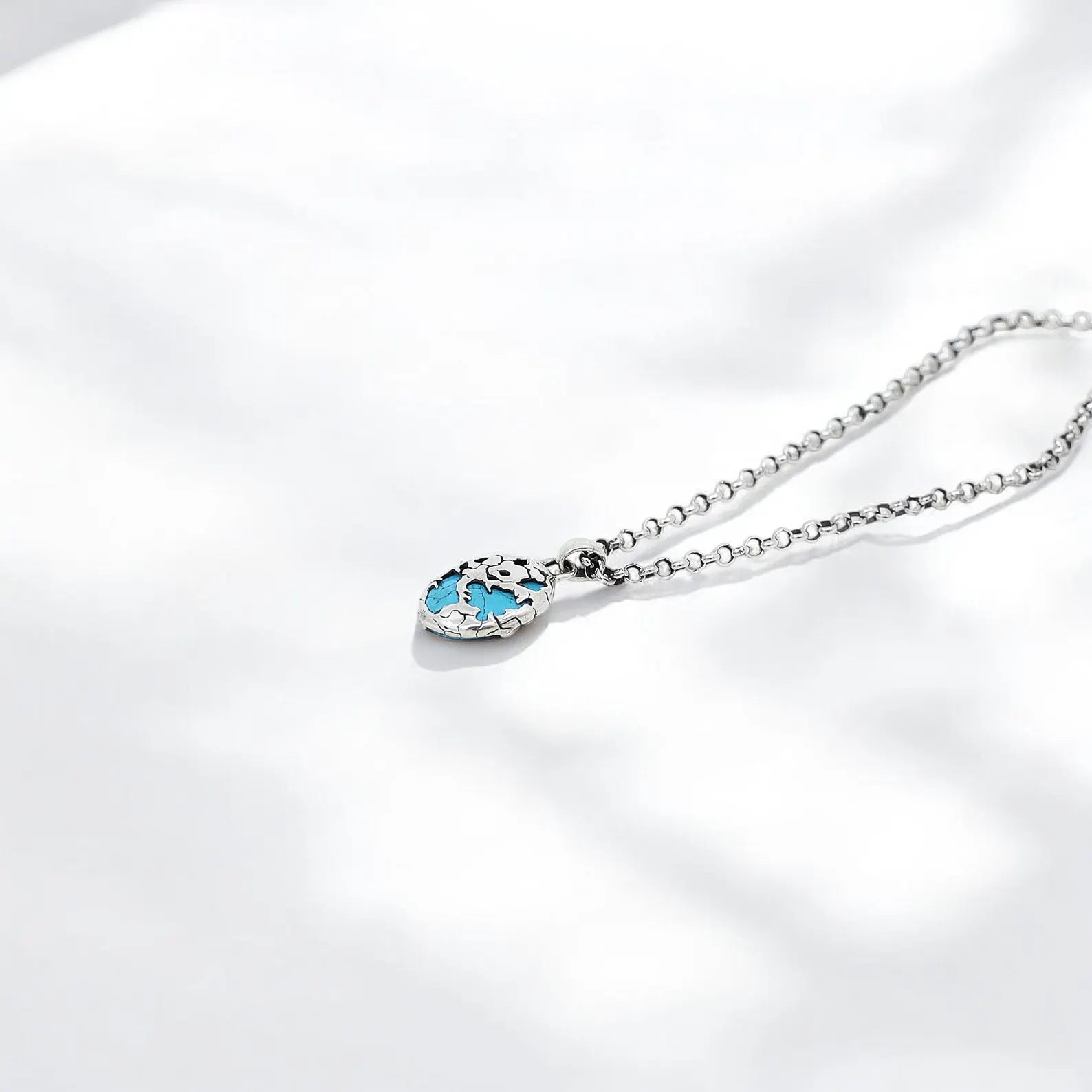 This one-of-a-kind turquoise gemstone necklace features a handcrafted silver pendant symbolizing global unity and oceanic inspiration. The detailed patterns and rich blue hues make it a standout piece in any jewelry collection.