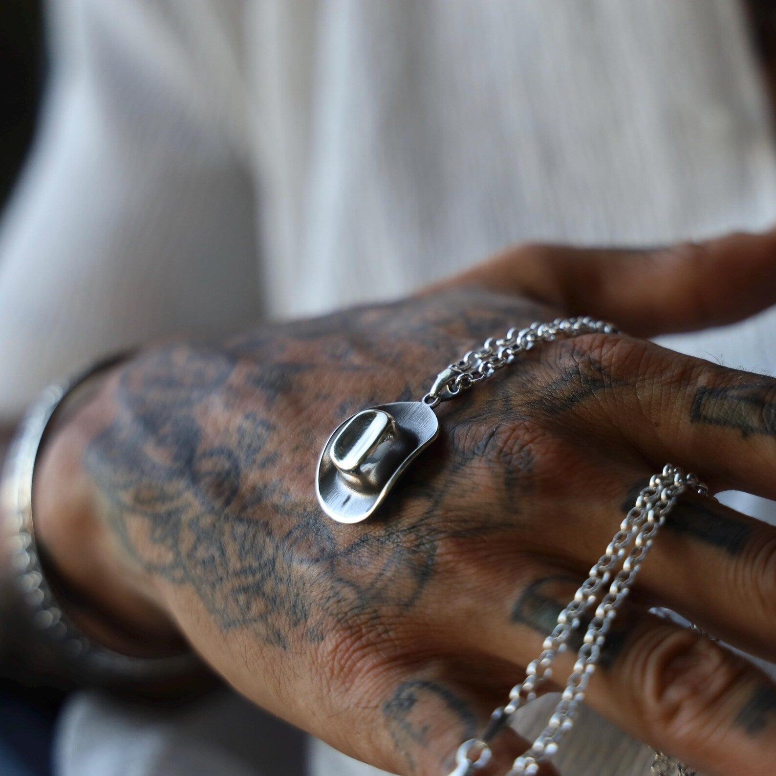 Detailed shot of a unisex silver necklace featuring a cowboy hat charm, handcrafted with a matte brushed finish for a rustic and authentic look, ideal for everyday wear or special gifts.
