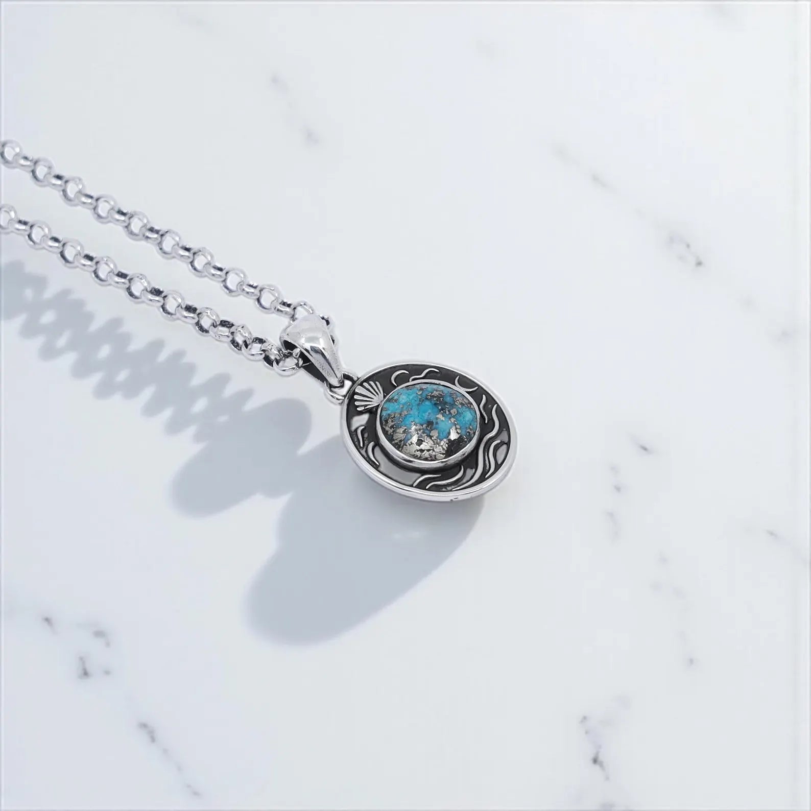 Elegant silver chain necklace with oval pendant housing a natural turquoise stone, designed with maritime motifs to create a vintage coastal look, handmade and polished to enhance its rustic charm.