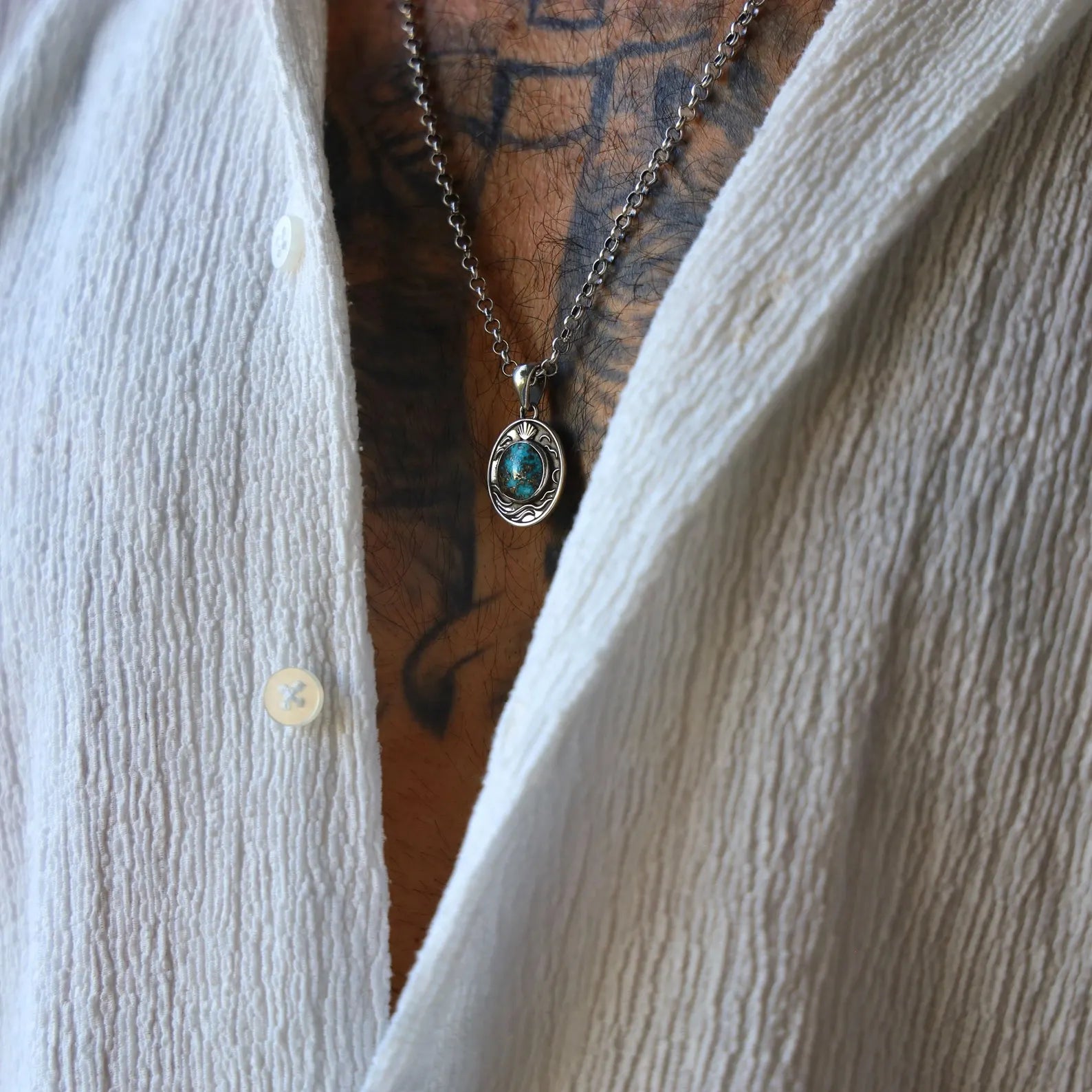 Elegant silver chain necklace with oval pendant housing a natural turquoise stone, designed with maritime motifs to create a vintage coastal look, handmade and polished to enhance its rustic charm.