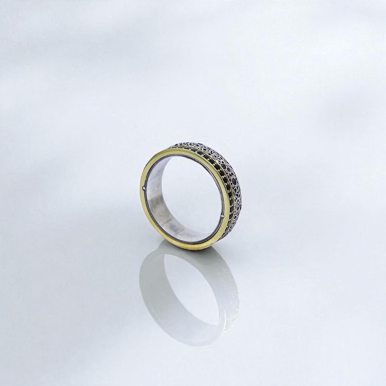 Angled perspective of one silver and gold-plated ring standing upright, showcasing the intricate engraved texture and polished inner band. This handcrafted unisex ring offers timeless elegance with a gothic twist, ideal for couples seeking unique, personalized wedding jewelry.