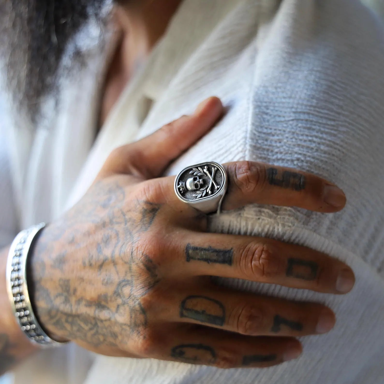 Close-up image of a handmade sterling silver skull signet ring for men, featuring a gothic-style crowned skull with crossbones, crafted with dark oxidized details and bold biker-inspired design elements.