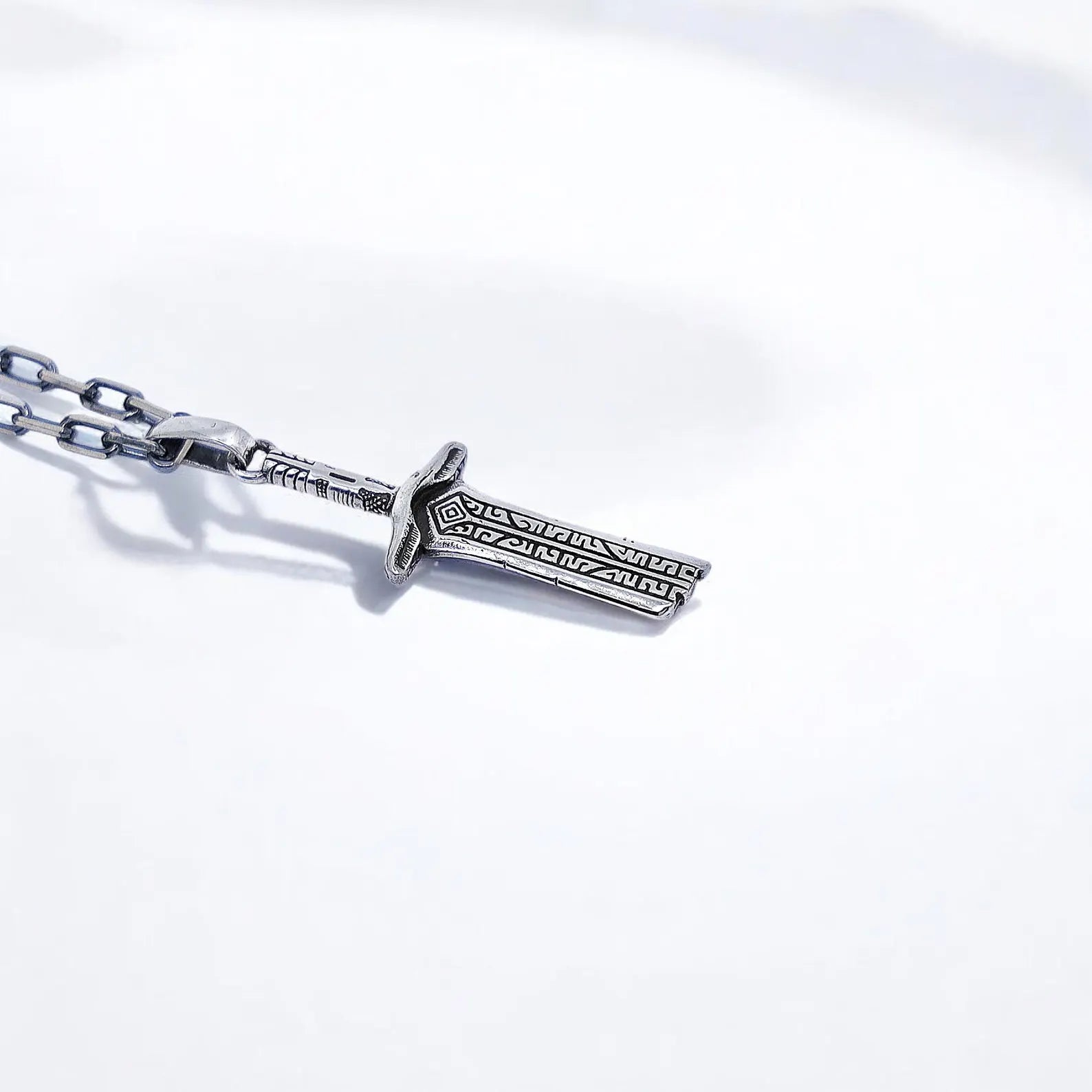 Symbolic handcrafted silver sword pendant designed with intricate medieval runes and forged to reflect warrior courage, resilience, and the mystic traditions of Viking and Gothic legends.
