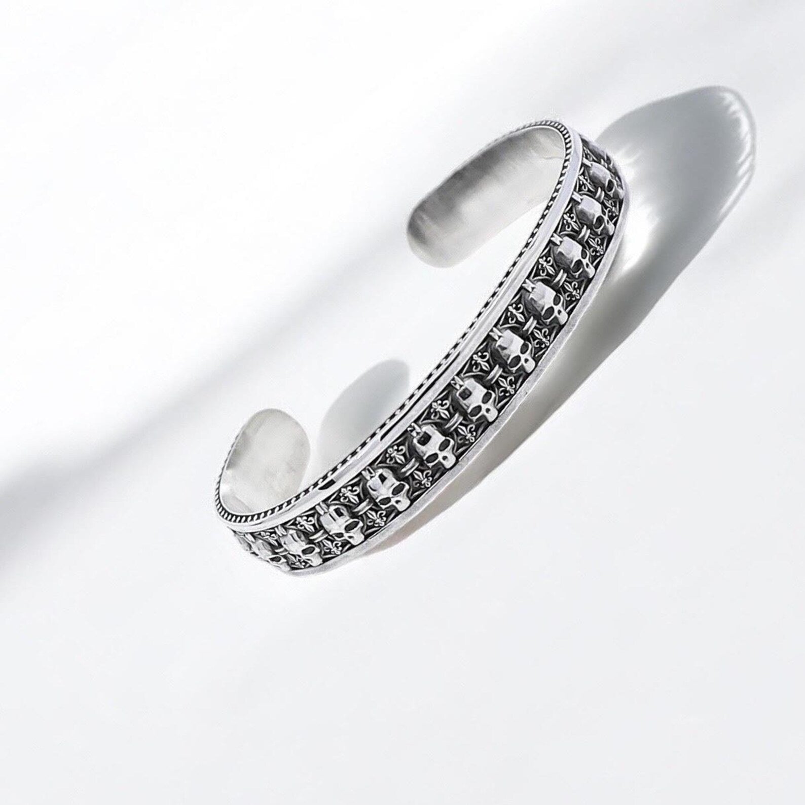 Handcrafted sterling silver gothic cuff bracelet for men featuring an intricately carved skull motif. This bold and adjustable statement piece combines rugged masculinity with refined gothic elegance. Designed to express individuality and fearlessness, it's a perfect accessory for those who embrace biker fashion and dark aesthetics.