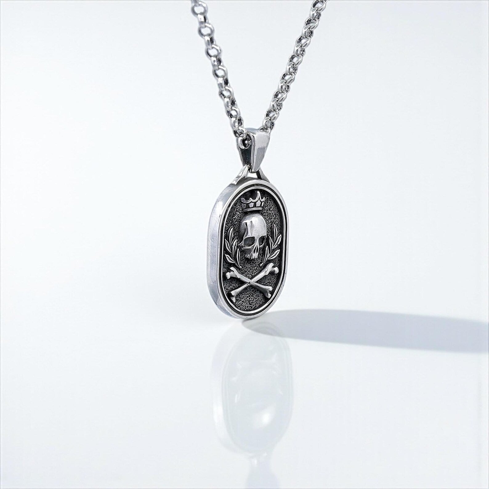 Edgy men's pendant necklace featuring a handcrafted silver skull with a royal crown and bone elements, blending gothic symbolism and biker culture for a unique and rebellious jewelry piece.