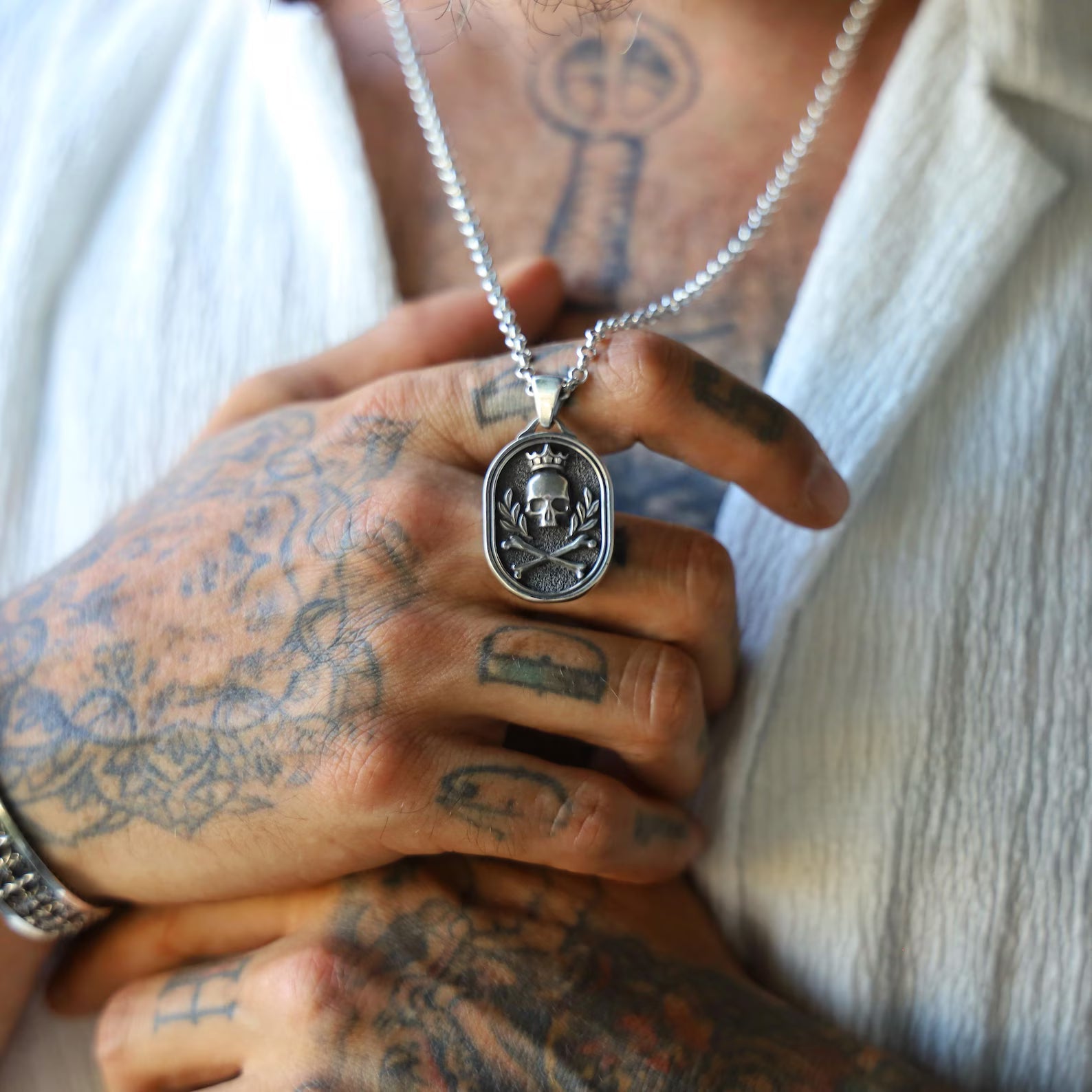 Close-up of a sterling silver gothic necklace with a skull and crown design, hanging from a thick chain; ideal for men who love edgy, punk-inspired, handcrafted biker jewelry.