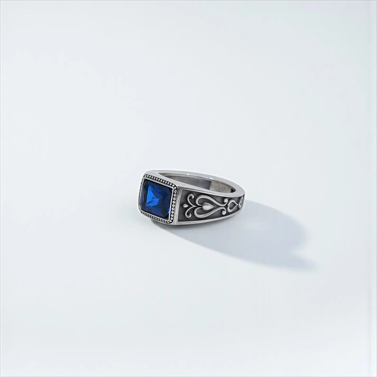 Statement jewelry piece for men featuring a deep blue emerald-cut stone in a detailed sterling silver band with handcrafted gothic motifs – perfect as a personalized anniversary or birthday gift.