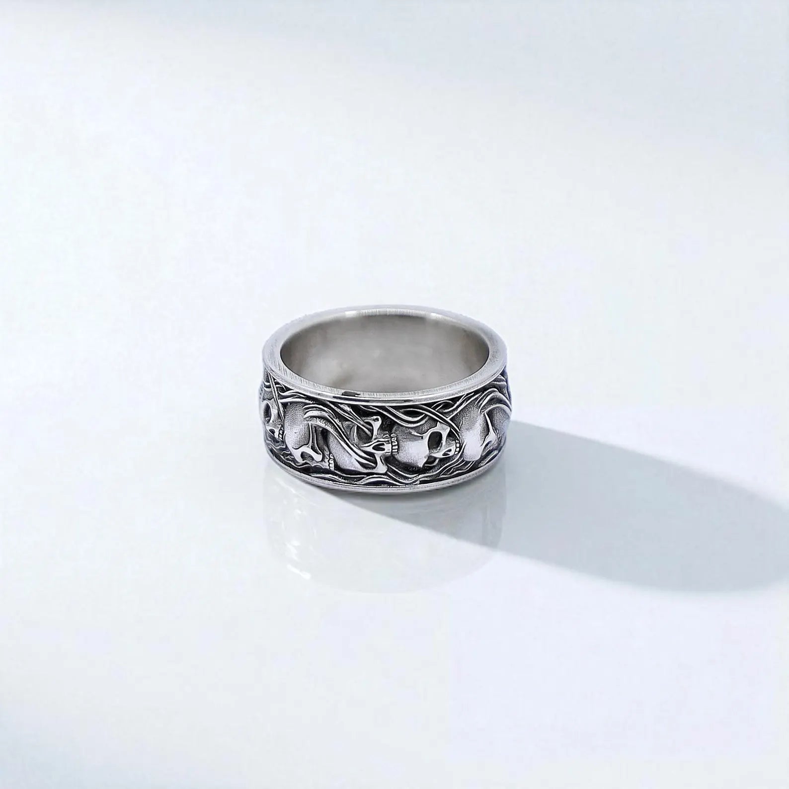 A gothic statement ring for men featuring a wide 925 silver band with multiple skulls in a continuous design. The handcrafted detailing gives this piece an antique warrior vibe, perfect for Viking, biker, or metal-style enthusiasts. A timeless piece of dark fashion jewelry to wear or gift with meaning.