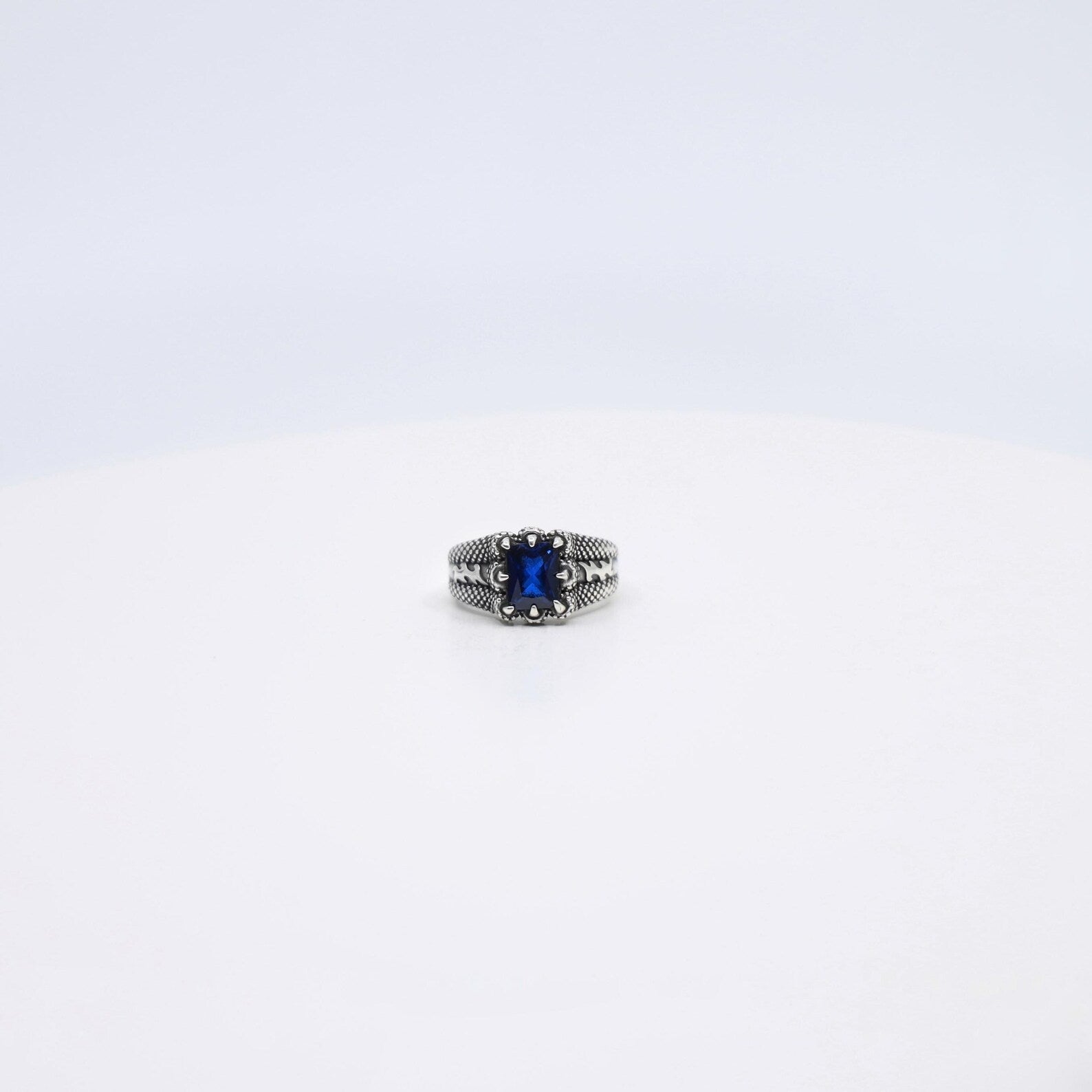 Styled on the finger, this minimalist sterling silver ring with an emerald cut sapphire stone shines with understated elegance. The unique gemstone’s deep blue hue and sleek claw setting make it a perfect choice for graduation gifts, Father’s Day surprises, or birthday presents for your husband or boyfriend. A sophisticated and versatile statement piece that celebrates refined taste and meaningful occasions.