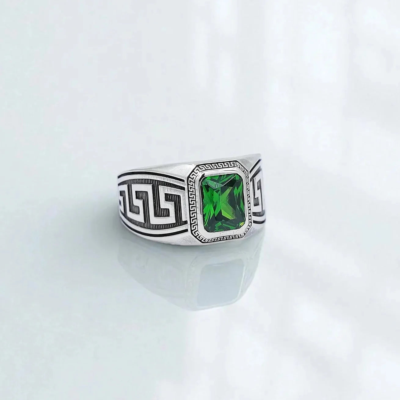 Front-facing view of a sterling silver men’s ring featuring an emerald-cut green gemstone framed by intricate Greek key patterns. This handcrafted statement ring blends classical Hellenistic symbolism with modern elegance, making it a perfect accessory for those who appreciate bold and refined jewelry.