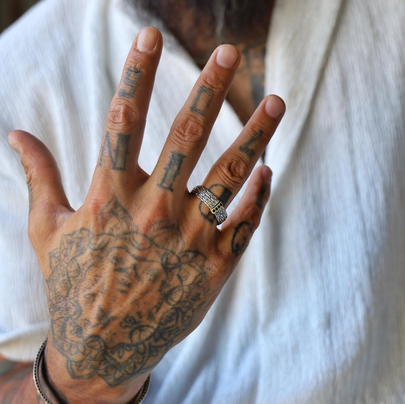 Detailed image of a sterling silver ring for men, featuring a wide, hand-textured band with luxurious gold accents and jet-black gemstones, ideal for those who appreciate high-end, handcrafted jewelry with gothic or biker influences.