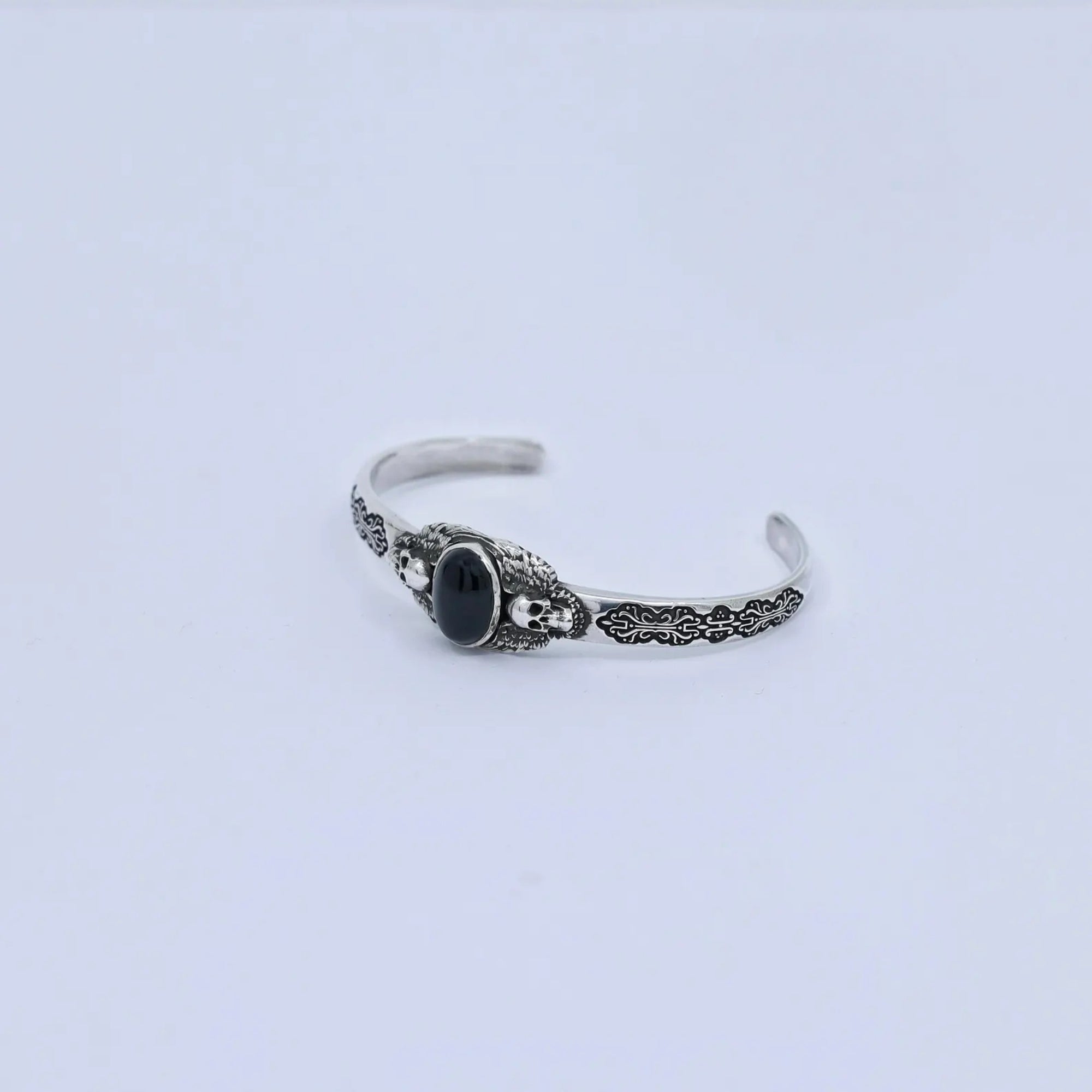 Stylish product photo of a men’s gothic bracelet made from 925 sterling silver with a bold black onyx centerpiece. The twin skull details symbolize power and resilience, making it an ideal statement gift for him.