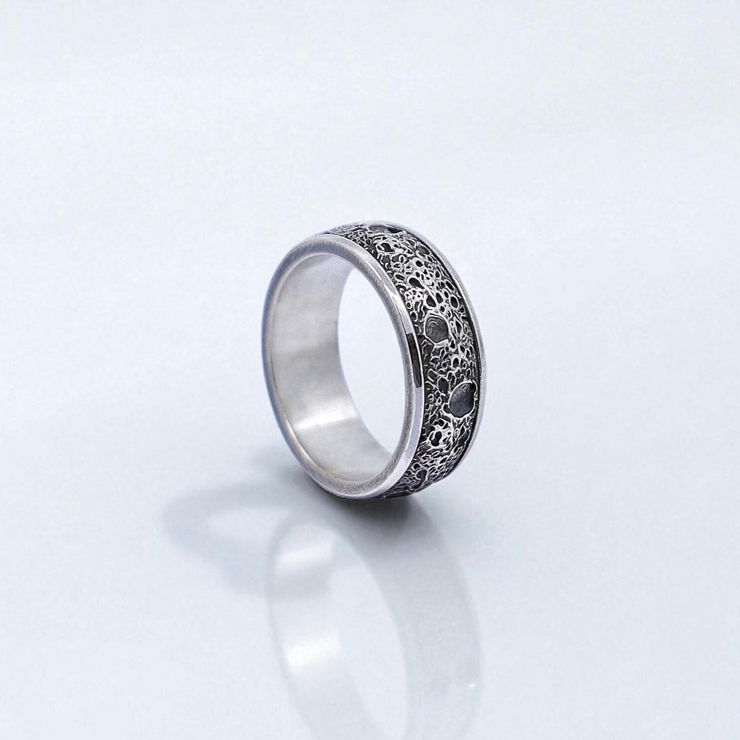 Front-facing view of a handcrafted sterling silver band ring for men, featuring a deeply textured vintage-style surface with intricate detailing. The oxidized finish enhances the gothic minimalist aesthetic, making it a timeless and sophisticated statement piece.