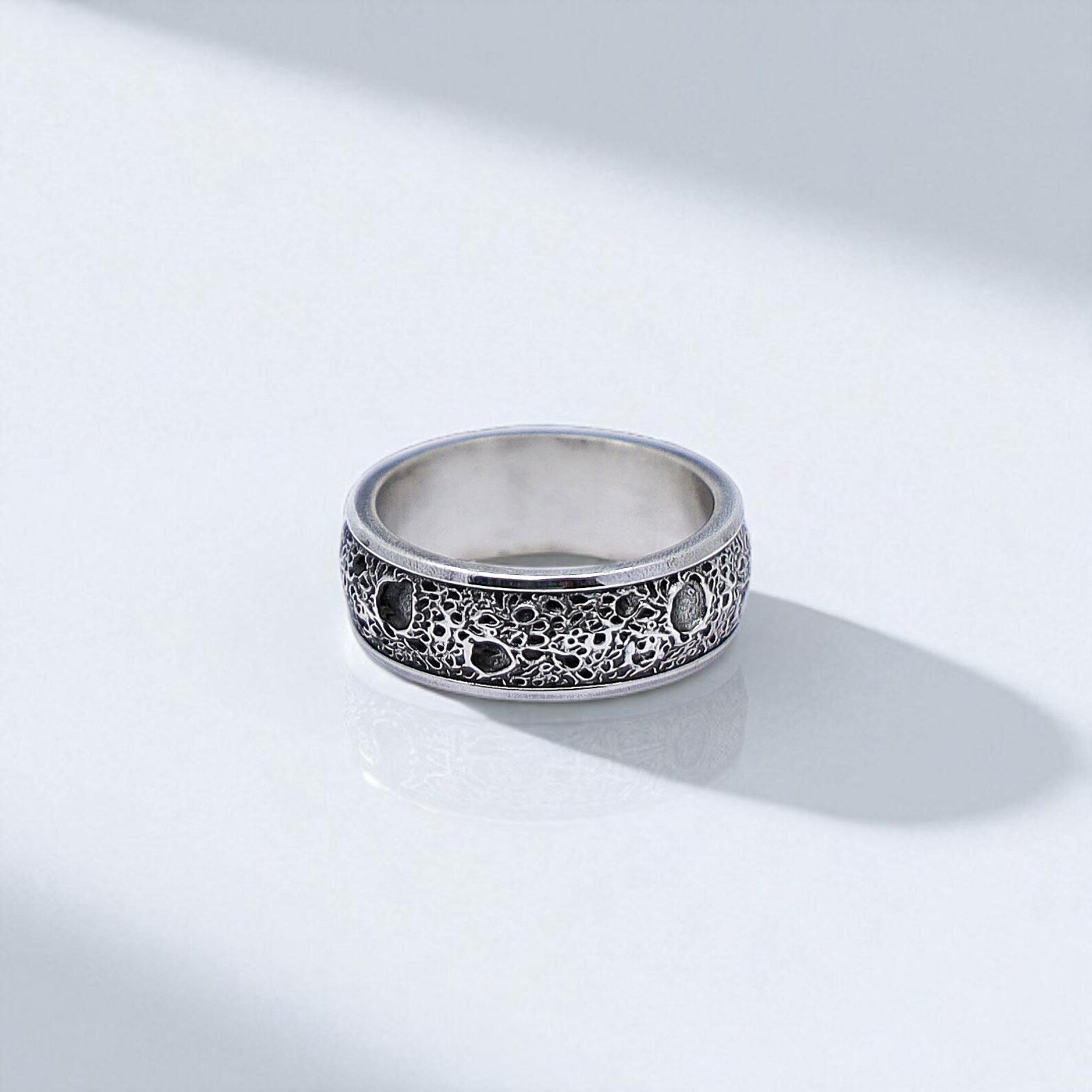 Top-down view of a sterling silver textured ring, highlighting the handcrafted details and subtle depth of the oxidized surface. This gothic-style band combines elegance and rugged charm for a bold everyday accessory.