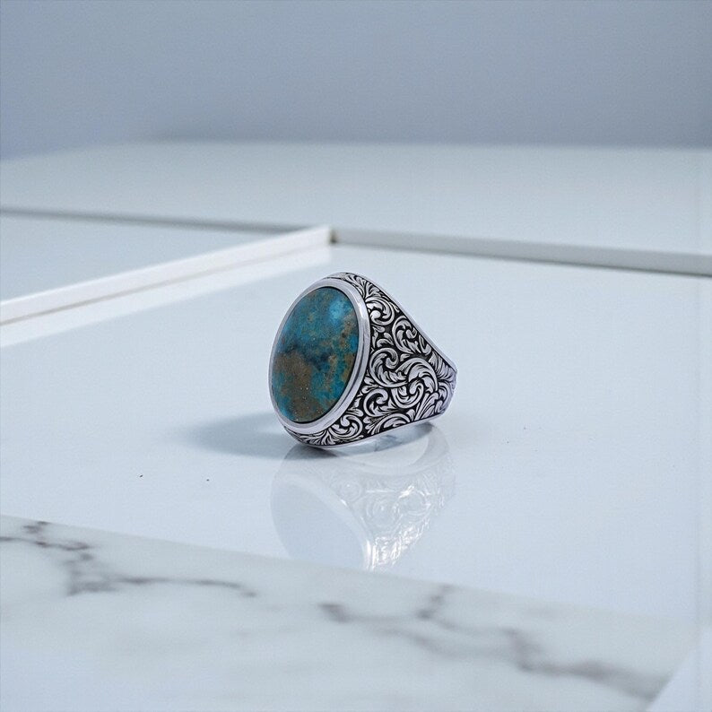 Side profile view of a handcrafted sterling silver signet ring with ornate Baroque floral engravings and polished natural turquoise gemstone