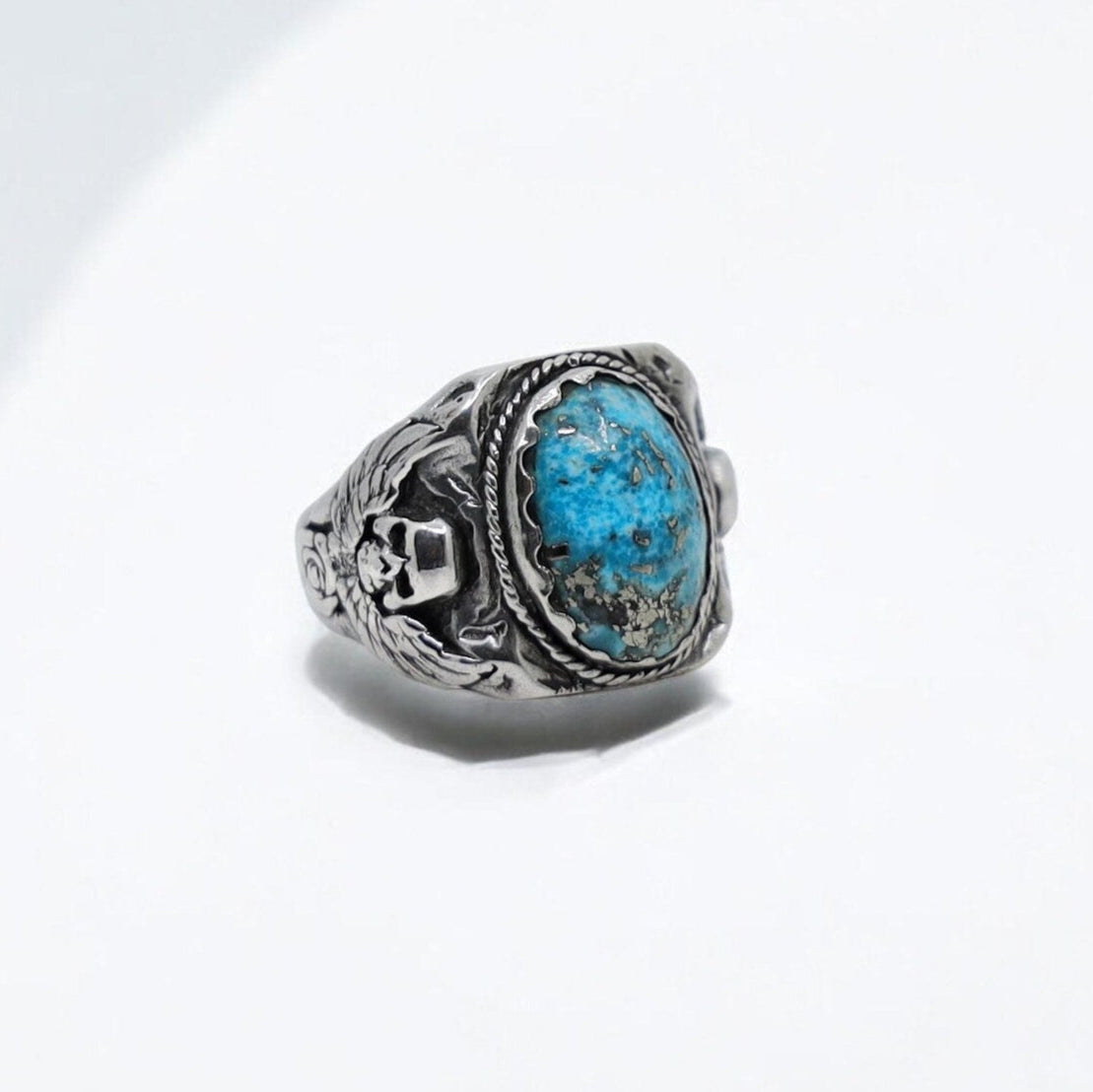 Handcrafted turquoise skull ring for men made from 925 sterling silver, designed with a bold biker aesthetic and gothic flair. This unique piece features a genuine turquoise gemstone and engraved skull details, making it perfect for lovers of western and outlaw jewelry.