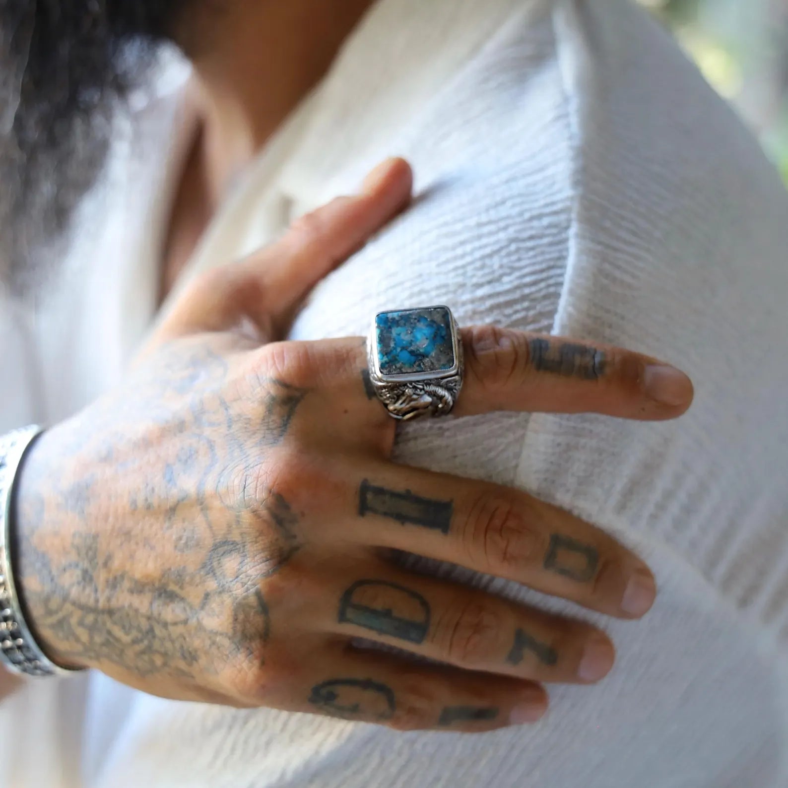 High-resolution shot of a square turquoise silver ring for men with horse and swirl patterns on the band, combining artisanal craftsmanship with symbolic western elegance.