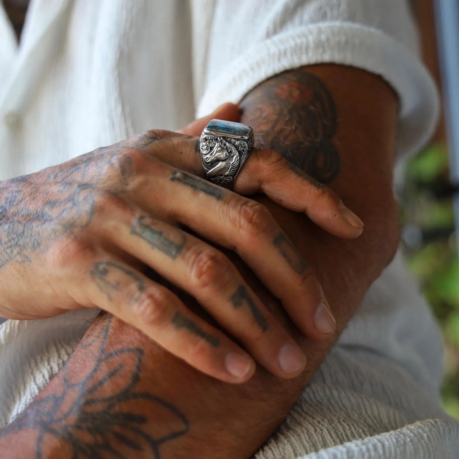 Handcrafted sterling silver ring for men featuring a bold square-cut natural turquoise gemstone set in a detailed western cowboy design. The band showcases an intricately engraved horse motif on each side, symbolizing strength and freedom. A perfect rustic statement ring for cowboy lovers, gemstone collectors, or unique handmade gift seekers.