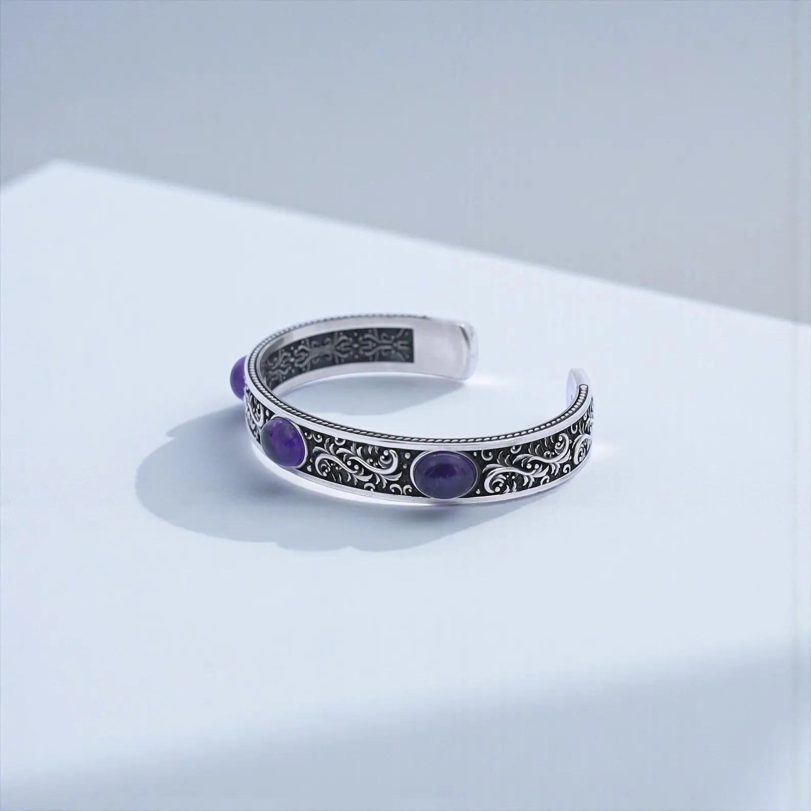 Statement men’s 925 sterling silver cuff bracelet with richly colored amethyst cabochons, handcrafted with detailed floral engravings and oxidized highlights, ideal for those seeking bold gemstone jewelry, spiritual protection, and premium artisan craftsmanship.
